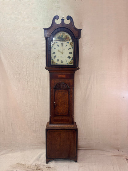 A antique Longbody Clock against a cloth Backdrop