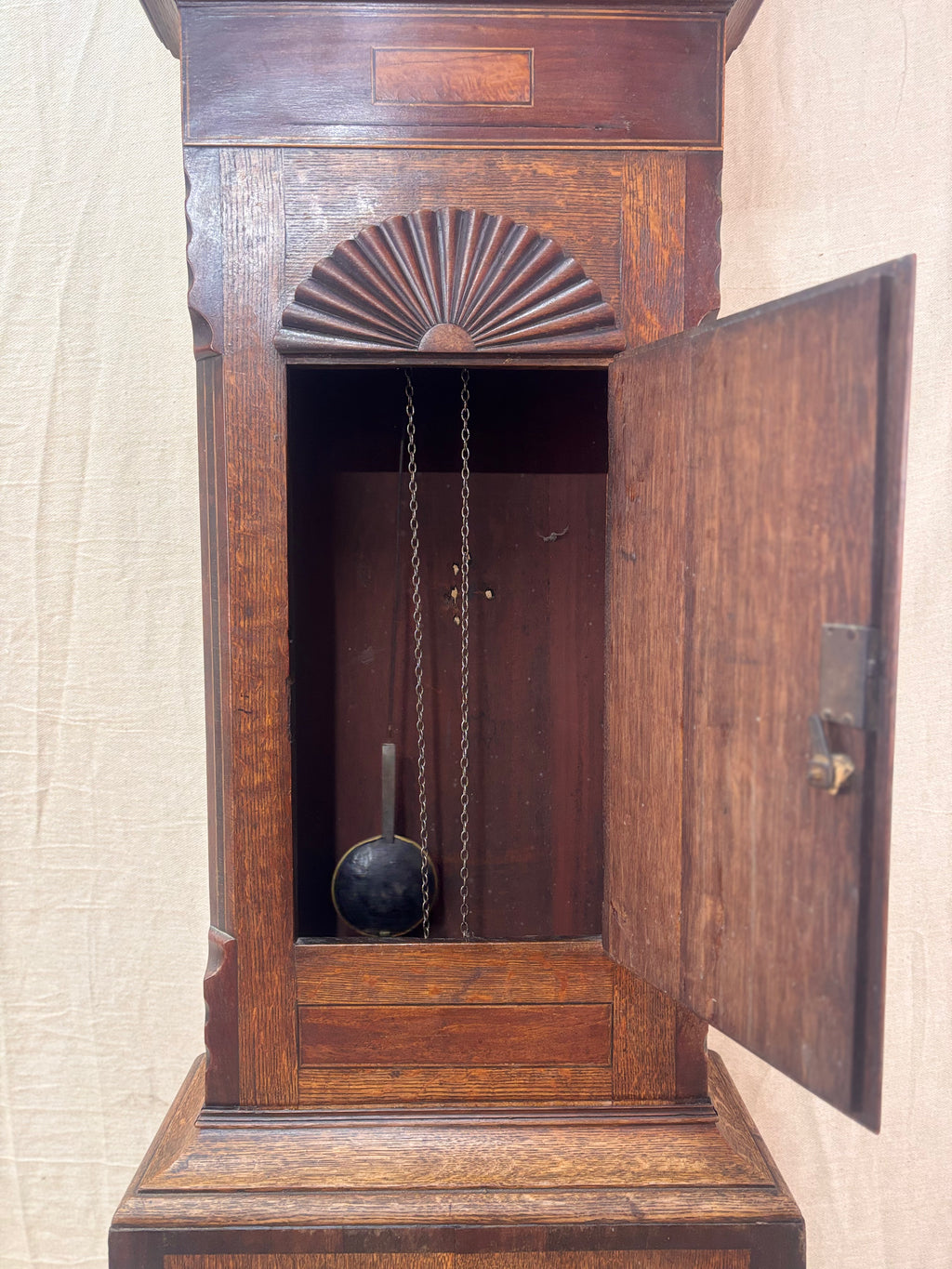 Open front door of a Grandfather clock against a cloth background