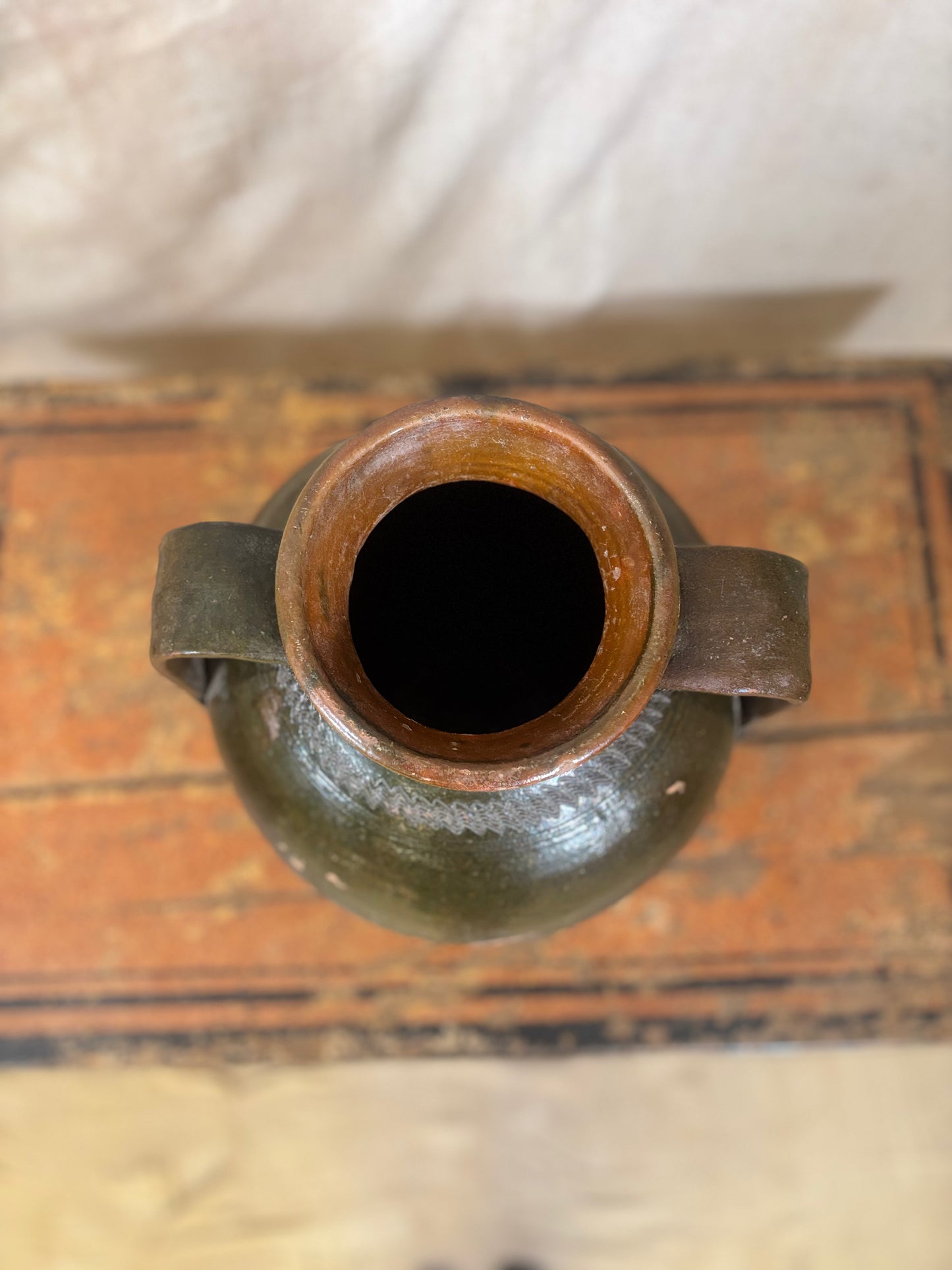 Top view of a green ceramic vase with a handle on a wooden surface.