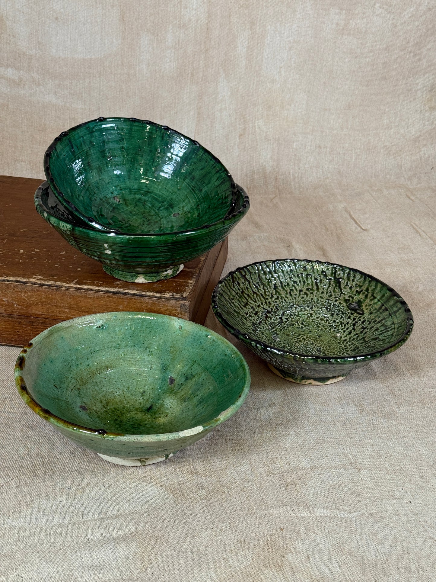 Three green ceramic bowls on a wooden surface