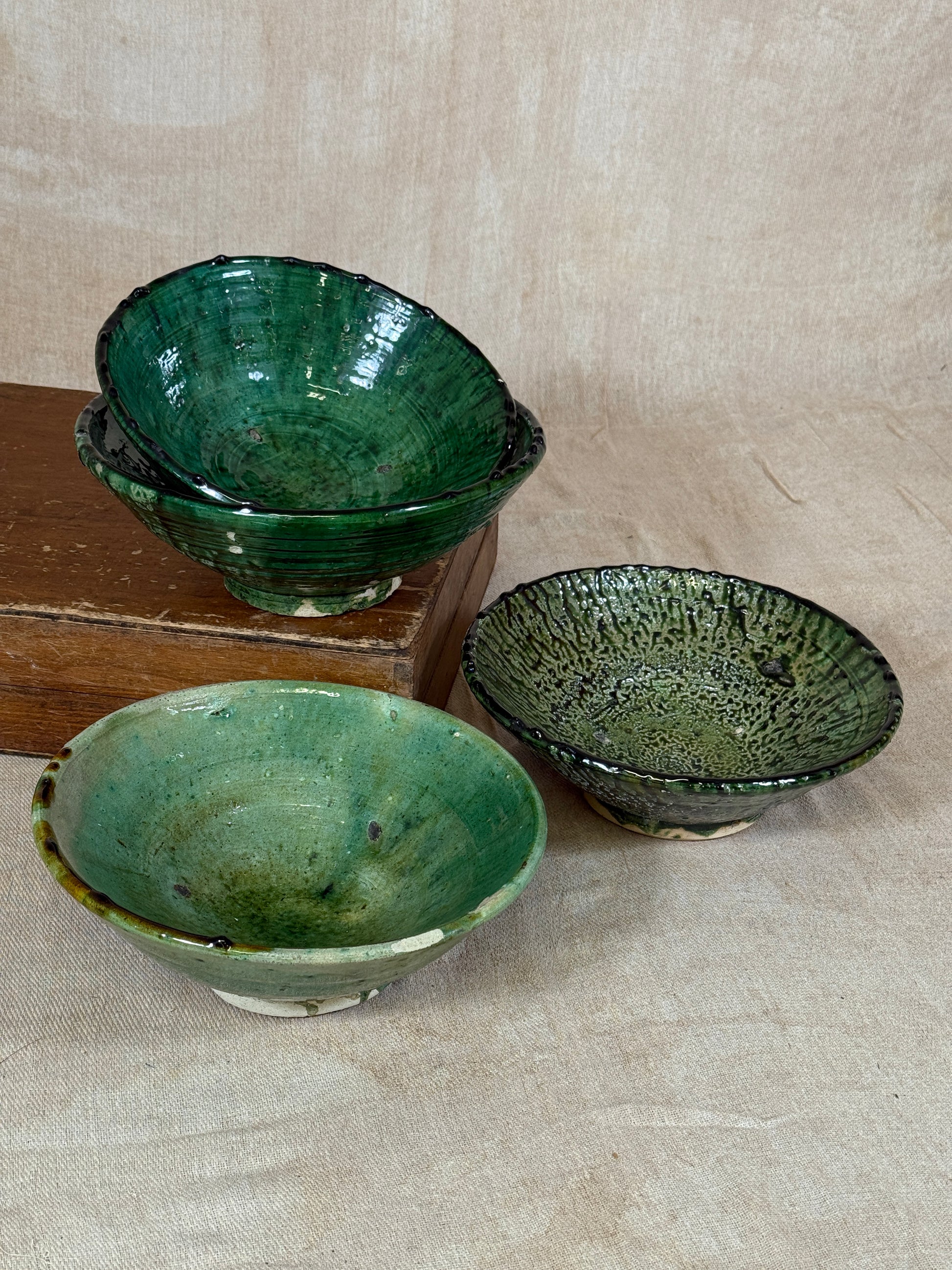 Three green ceramic bowls on a wooden surface