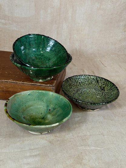 Three green ceramic bowls on a wooden surface