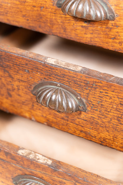 Close-up of a vintage wooden drawer with a ribbed metal pull handle, showing the warm brown wood grain and aged finish.