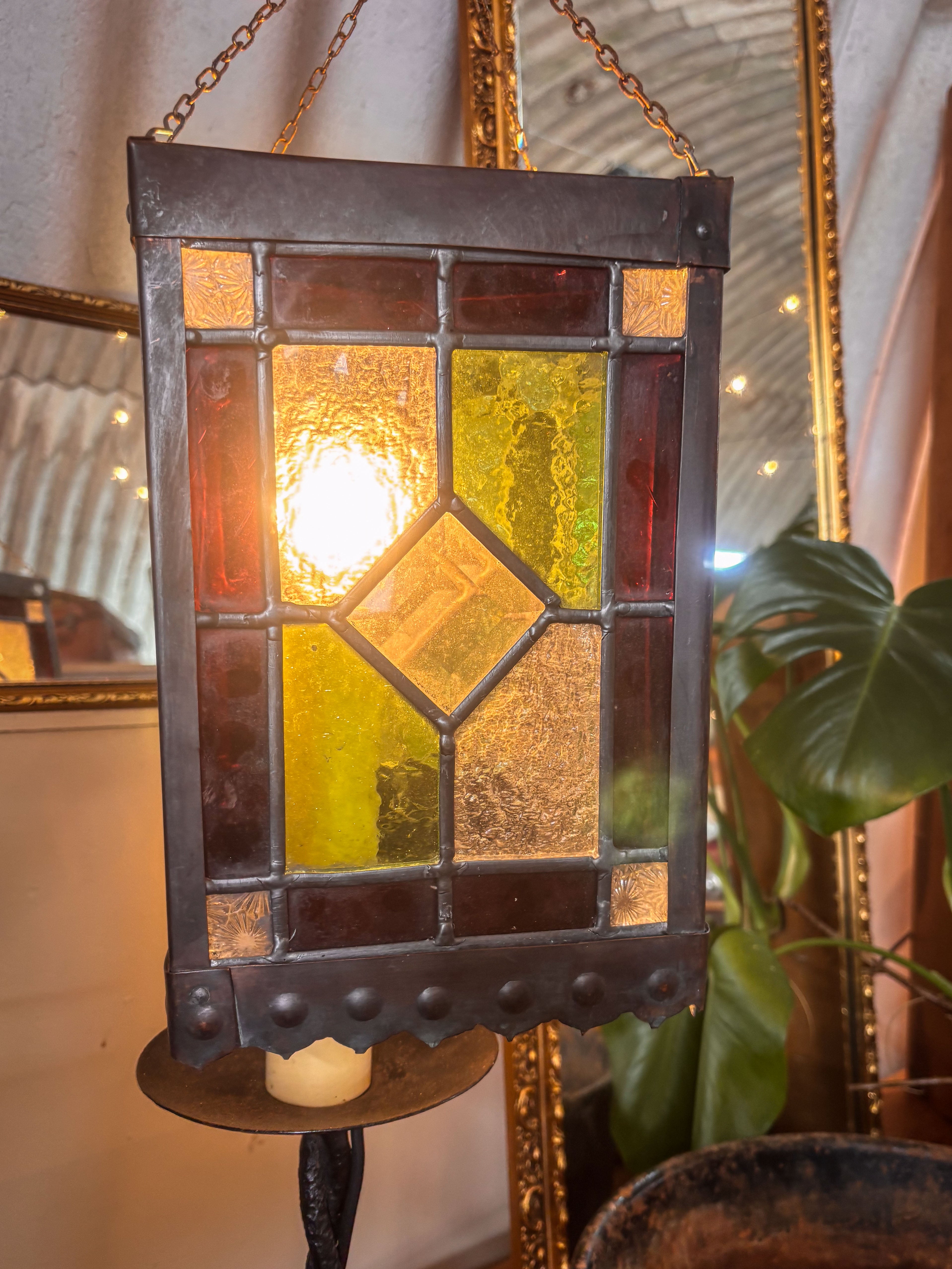 Stained glass hanging light fixture with a warm glow, surrounded by decorative elements.