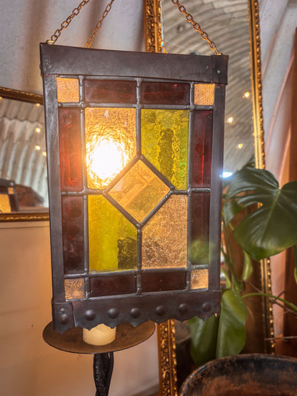 Stained glass hanging light fixture with a warm glow, surrounded by decorative elements.