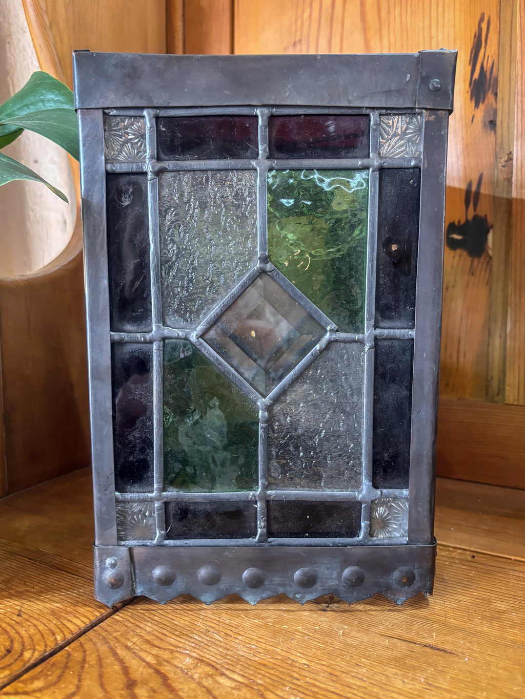 Decorative stained glass lantern with metal frame on a wooden surface