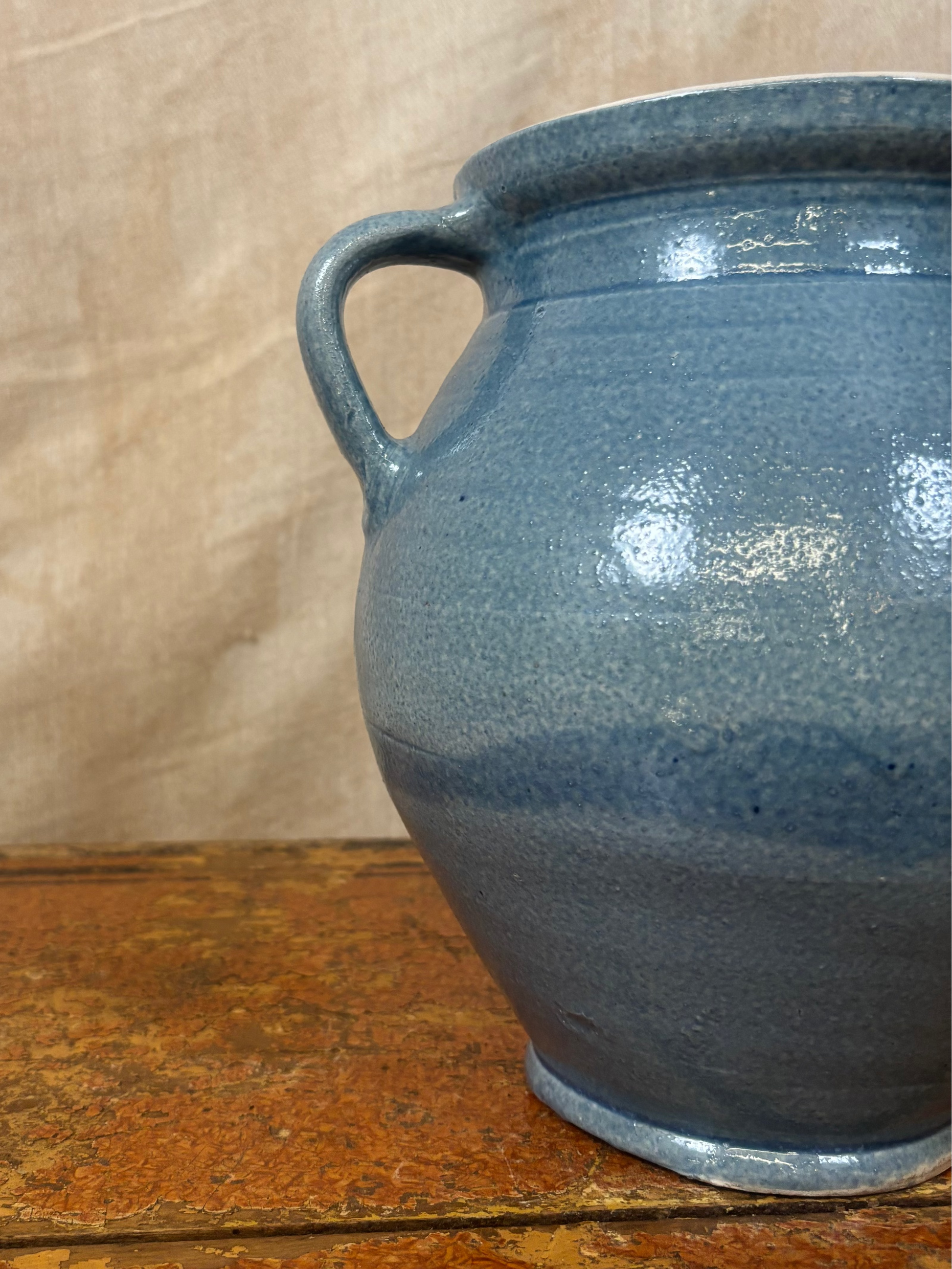 Blue ceramic jar on a wooden surface with a beige background