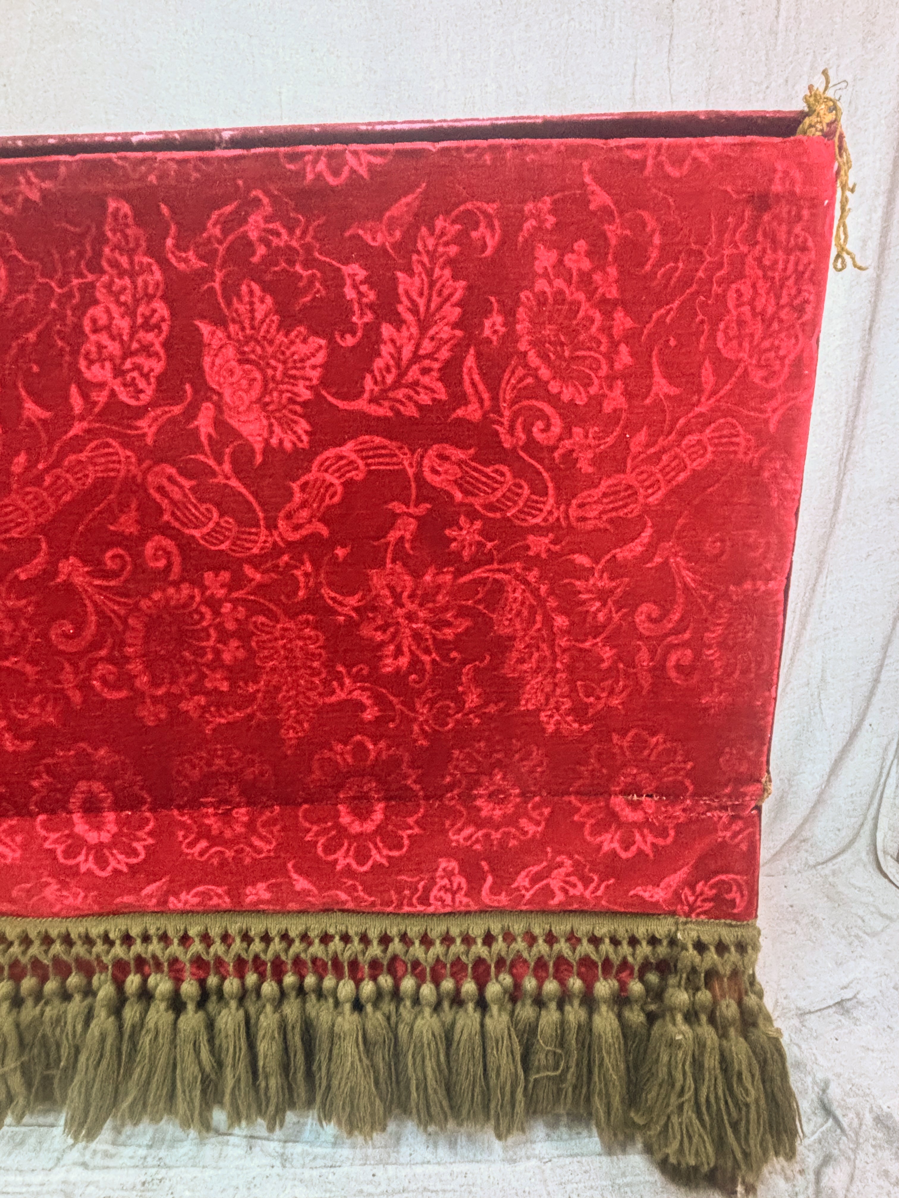 Red embroidered fabric with gold tassels on a white background