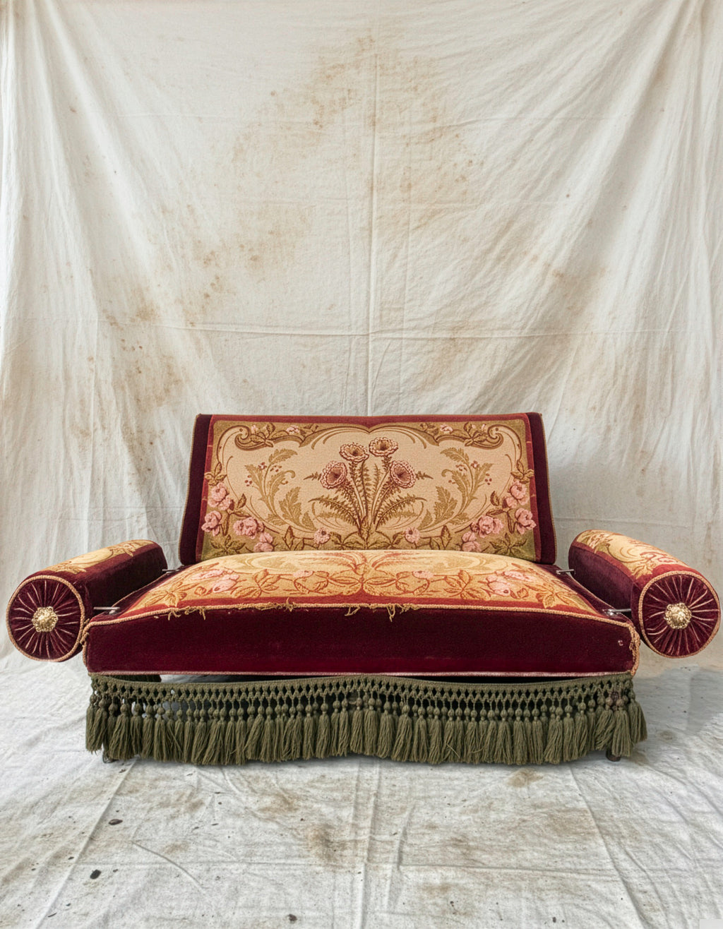 Decorative sofa with intricate patterns and fringes on a plain background