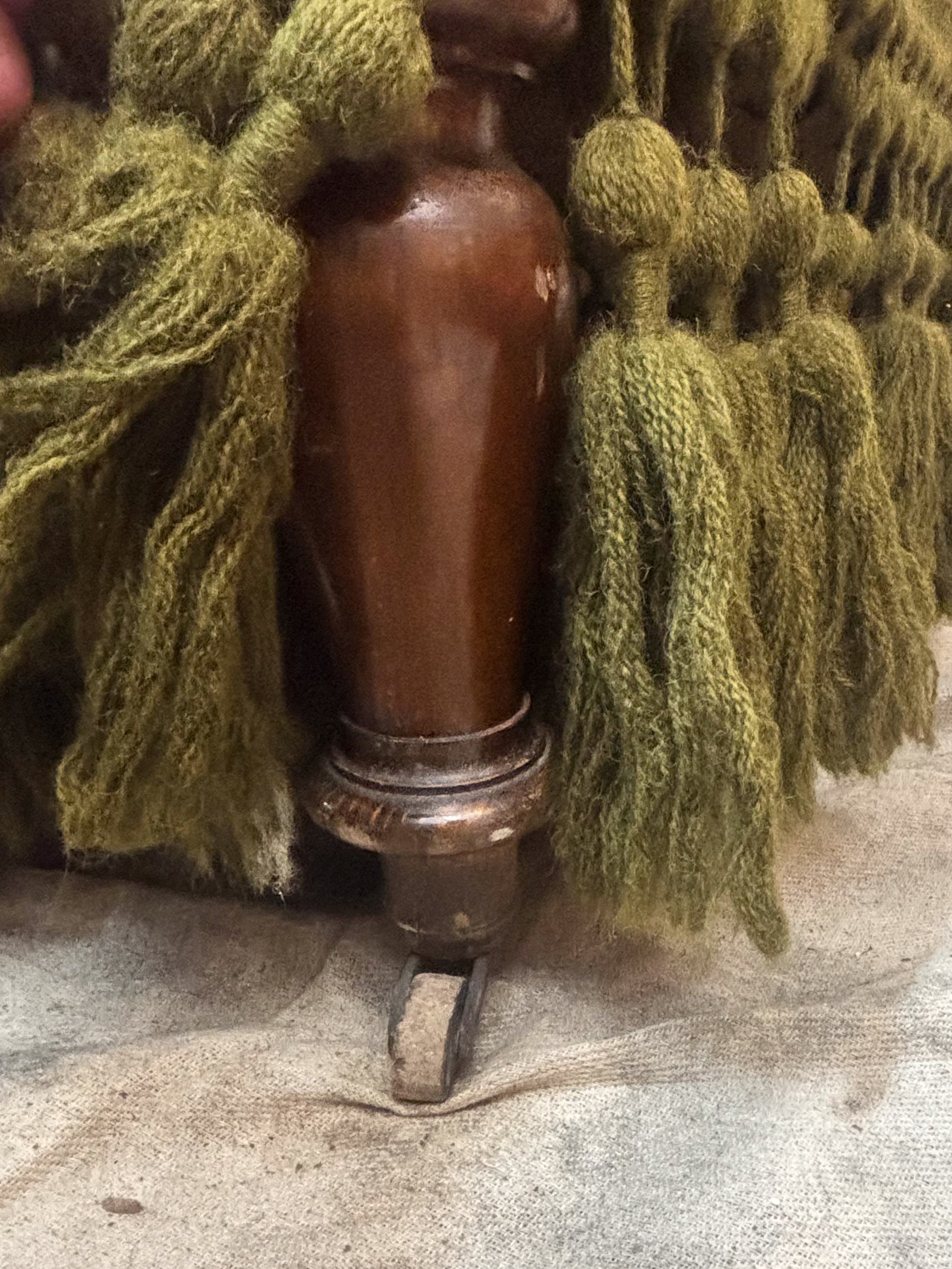 a turned wooden sofa leg and green fringe
