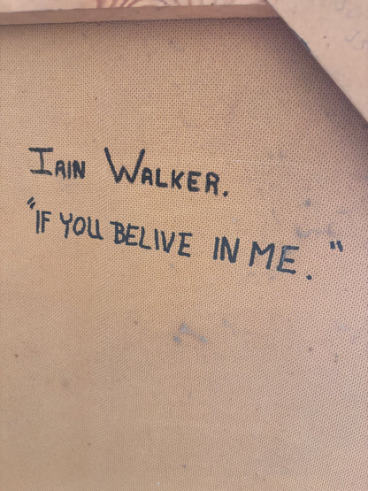 Close-up of a canvas or fabric artwork surface with handwritten text reading 'Iain Walker.' and the quote '"If you believe in me.