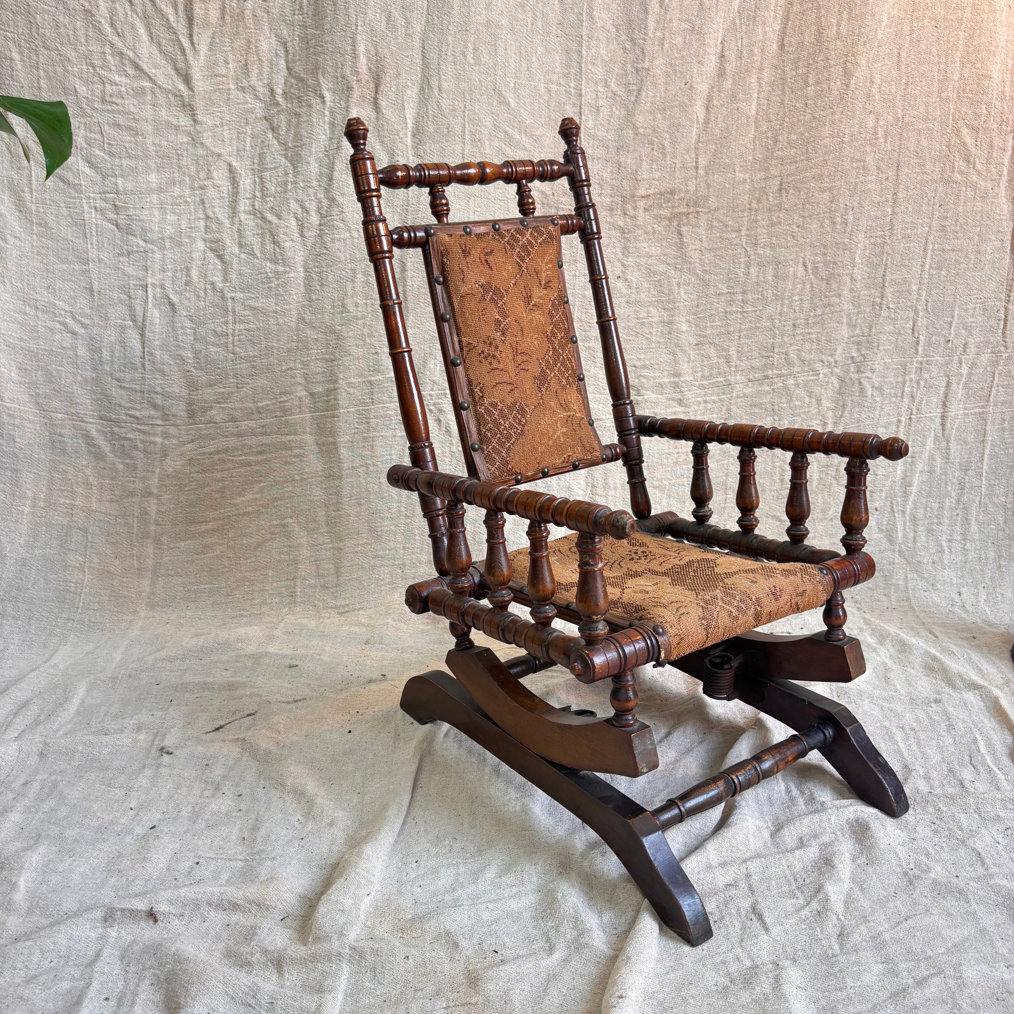 Vintage wooden rocking chair with patterned seat on a textured fabric background