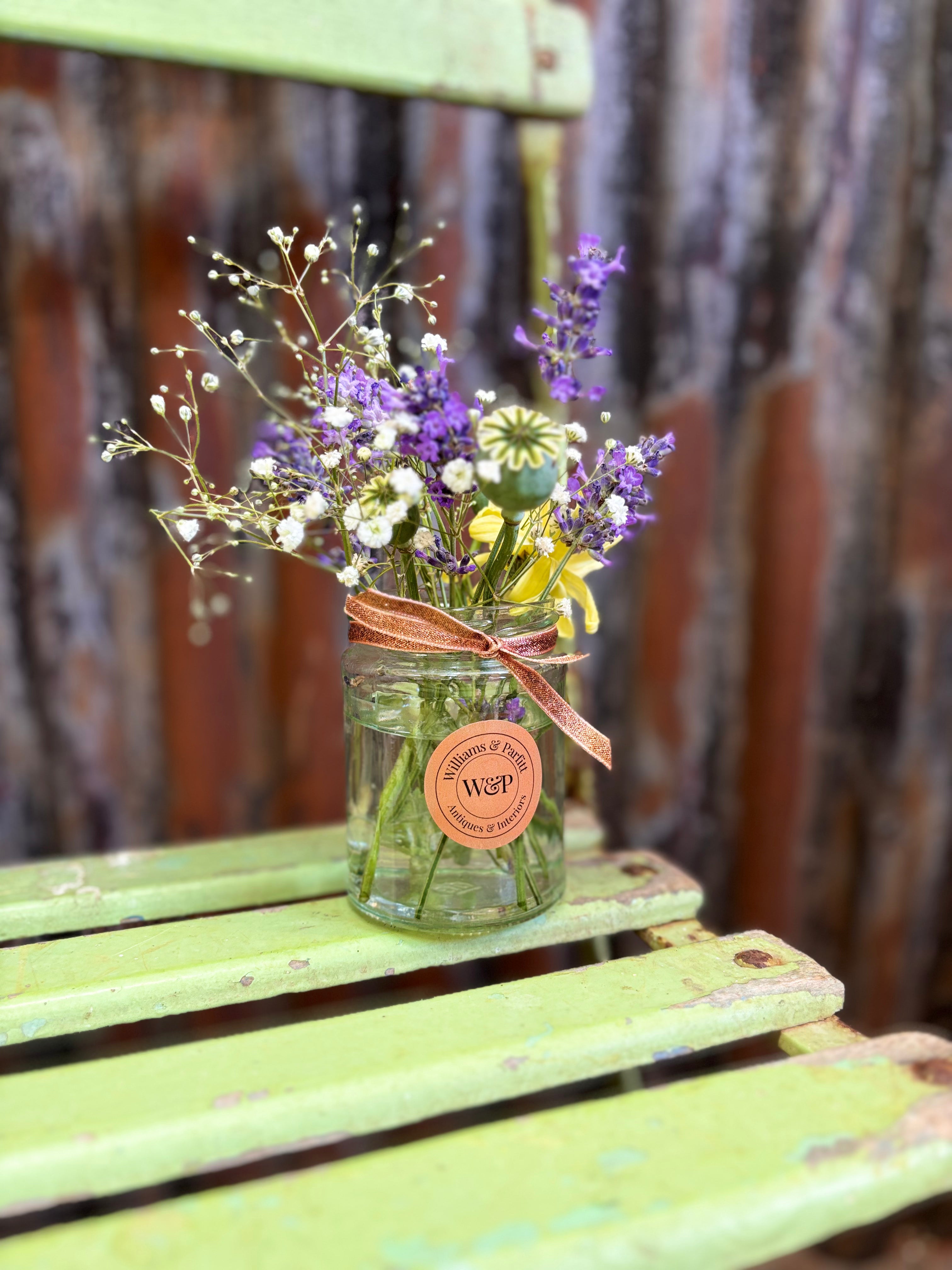 Jar of flowers with a decorative label on a rustic wooden surface