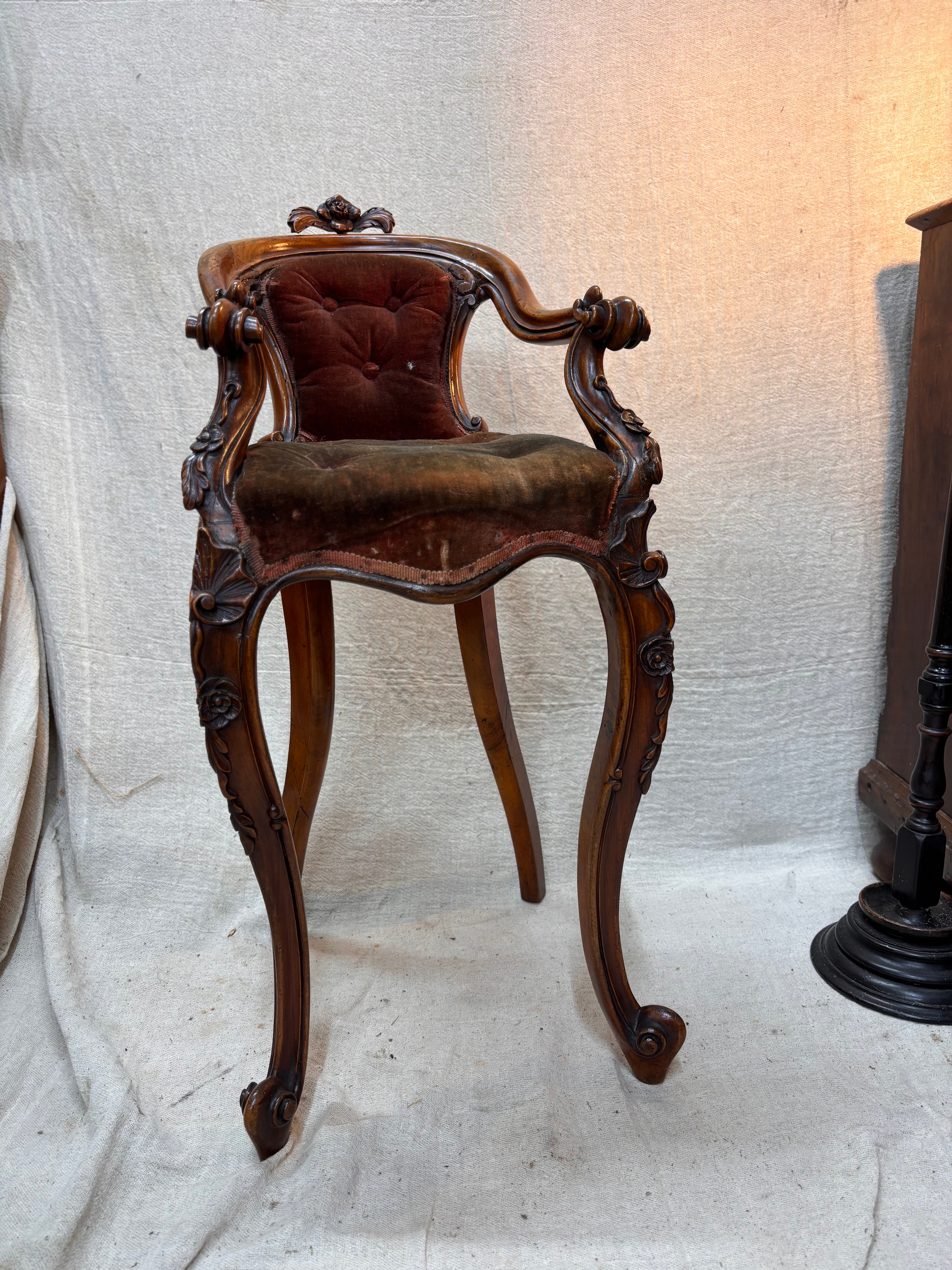 Victorian wooden chair with tufted cushion on a textured white background