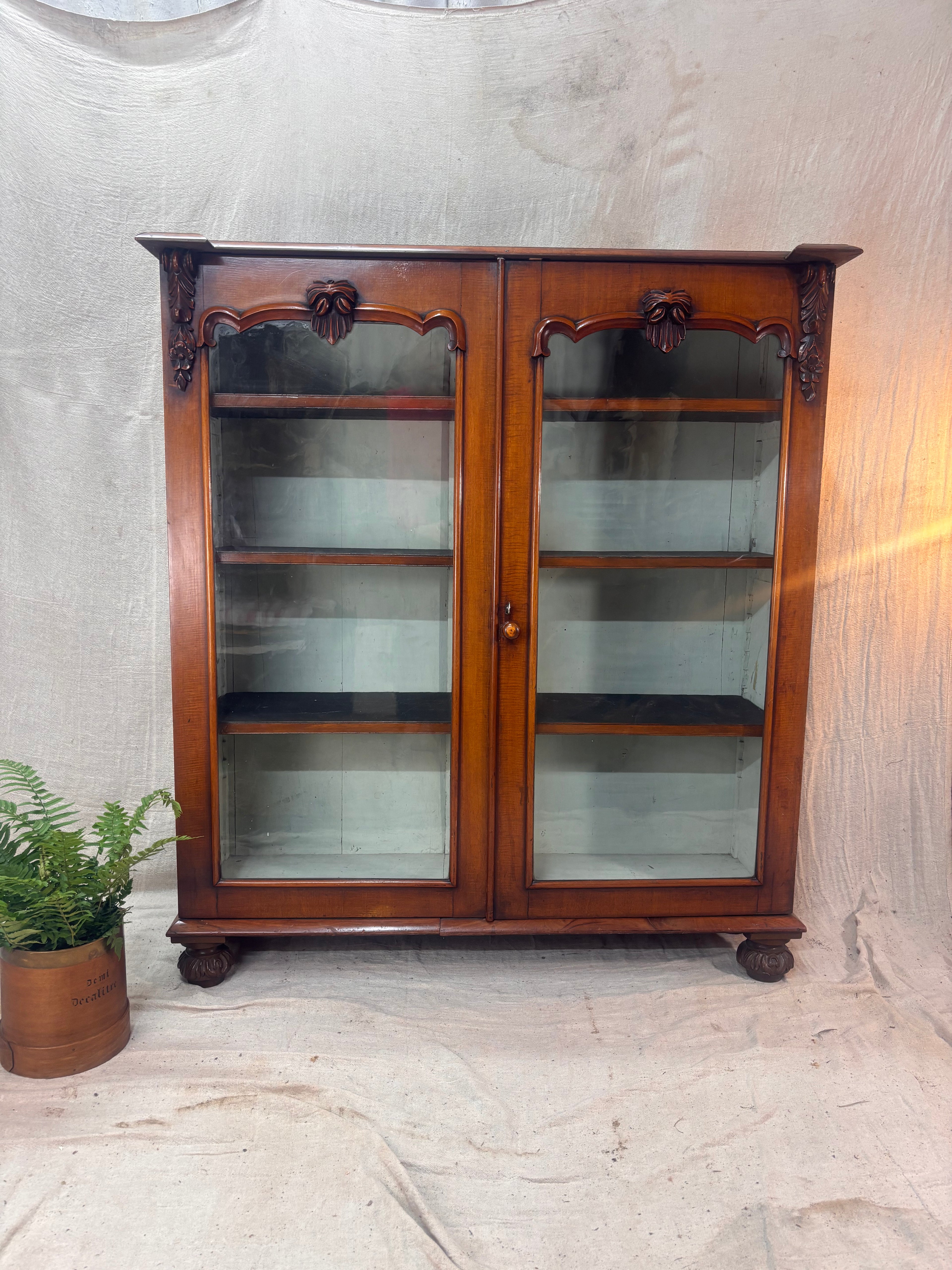 Wooden display cabinet with glass doors on a textured wall background