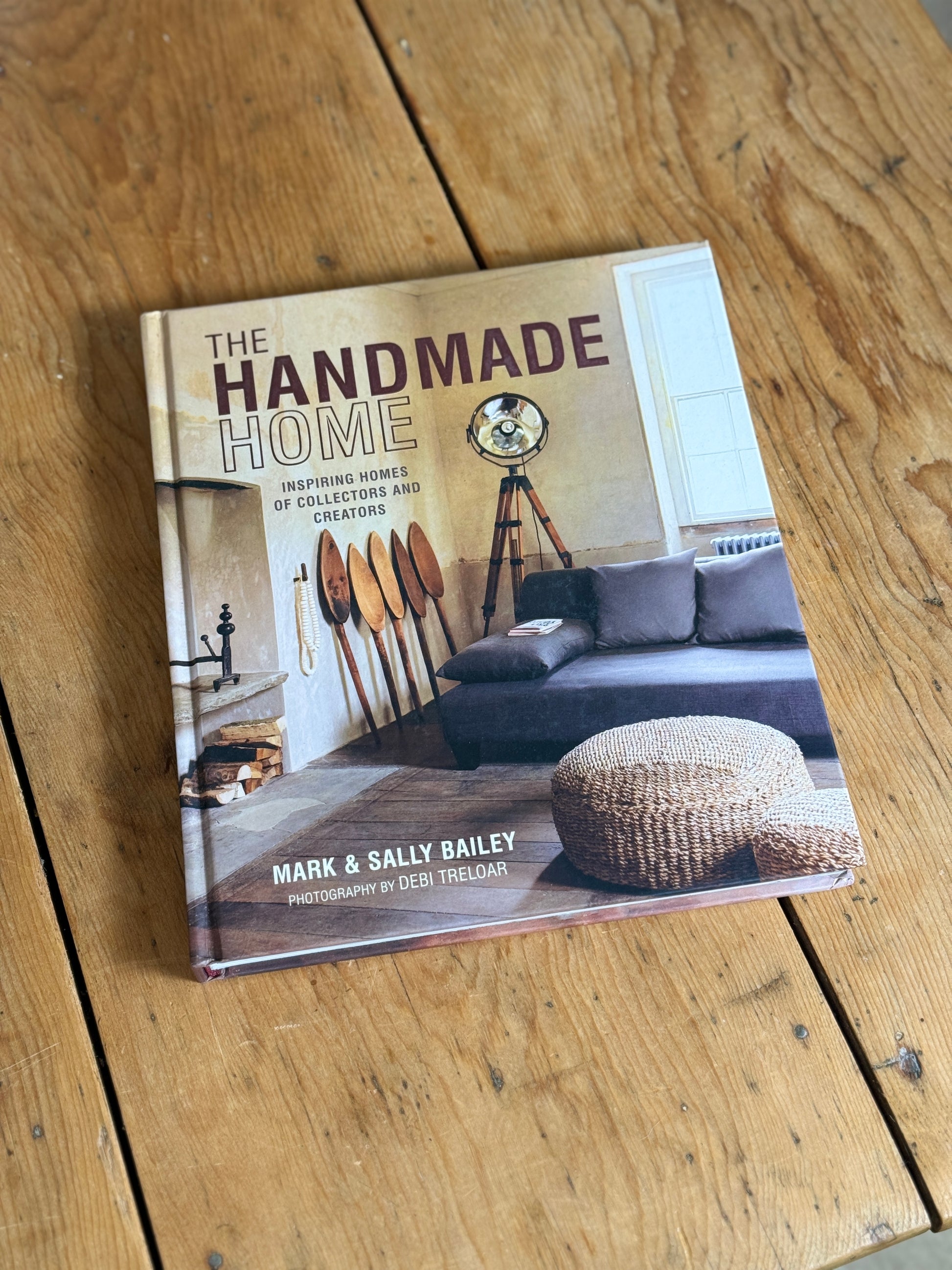 The Handmade Home book by Mark & Sally Bailey, featuring a rustic interior cover design, placed on a wooden plank surface.