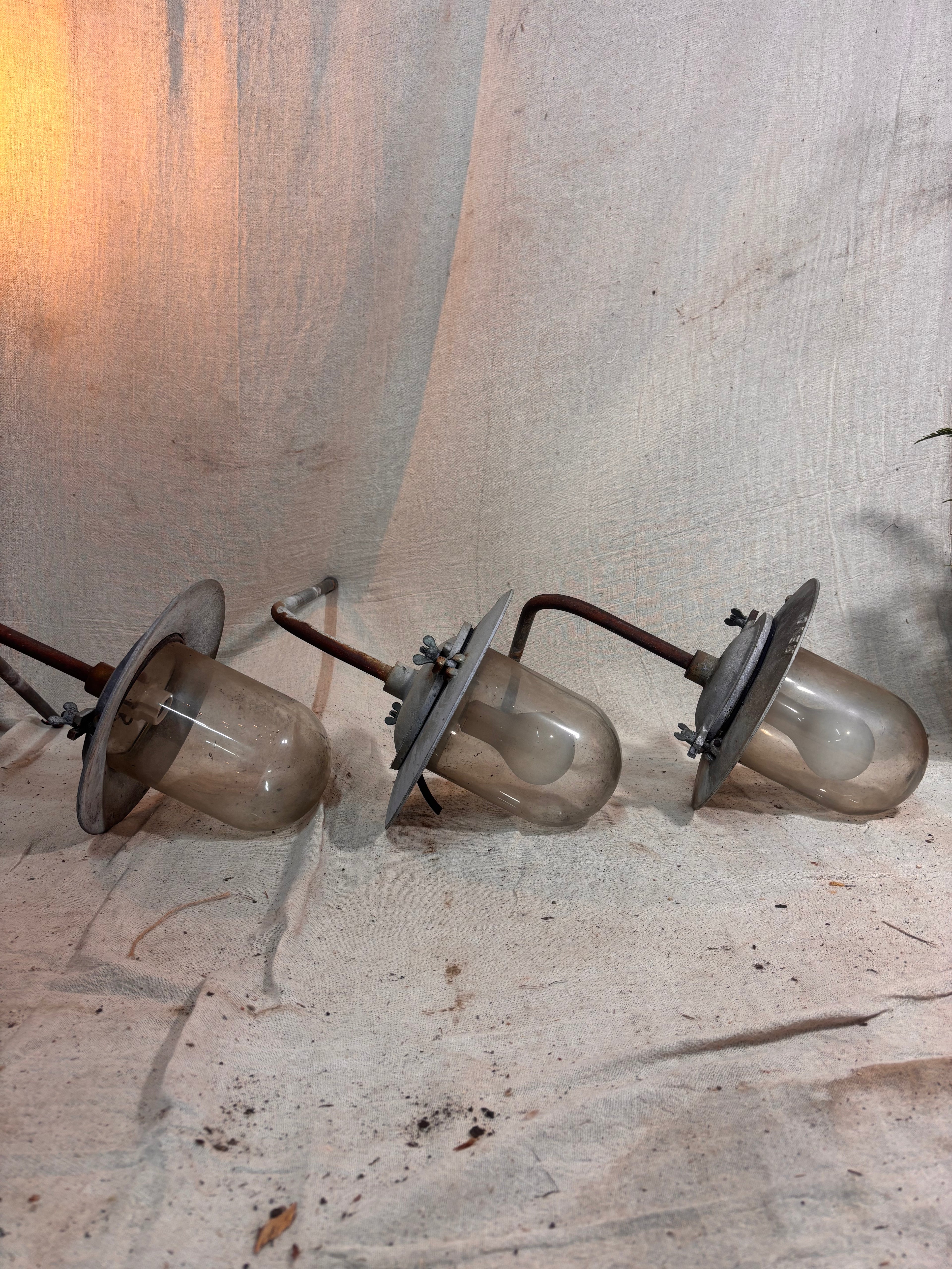 3 large industrial light fittings on a dirty floor