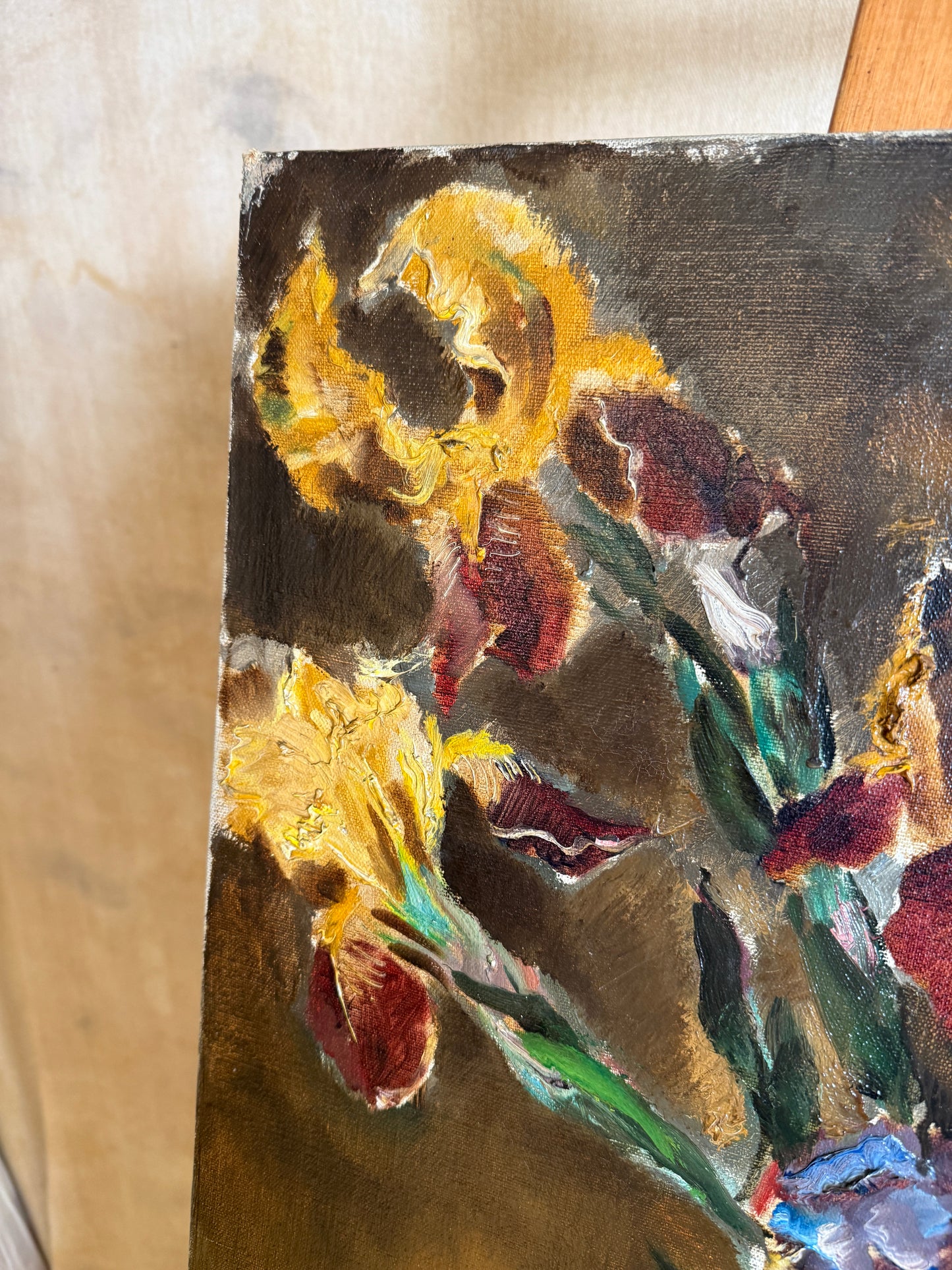 A close-up of an oil painting depicting yellow irises with textured brushstrokes in yellow, red, green, and dark brown tones.