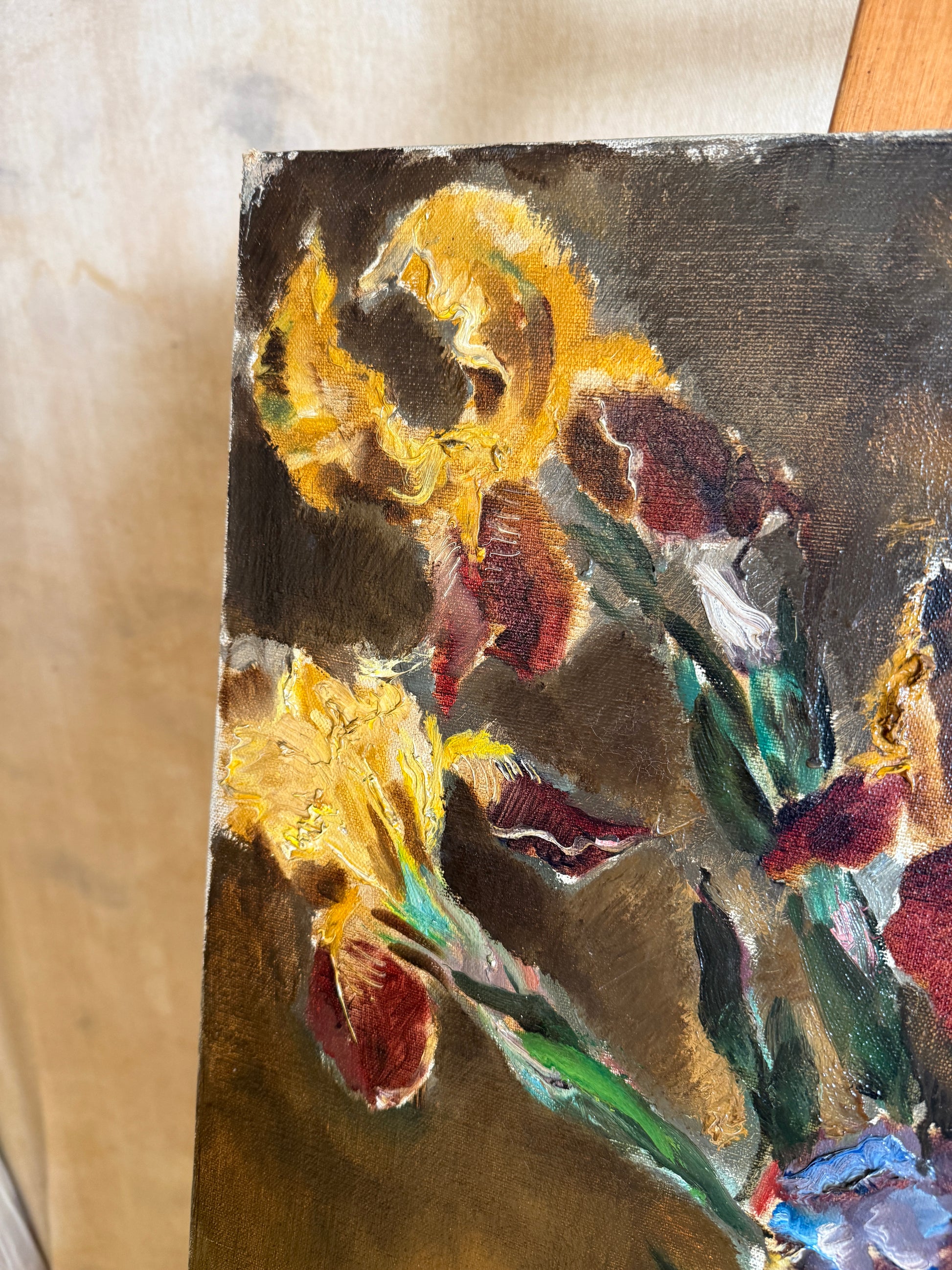 A close-up of an oil painting depicting yellow irises with textured brushstrokes in yellow, red, green, and dark brown tones.