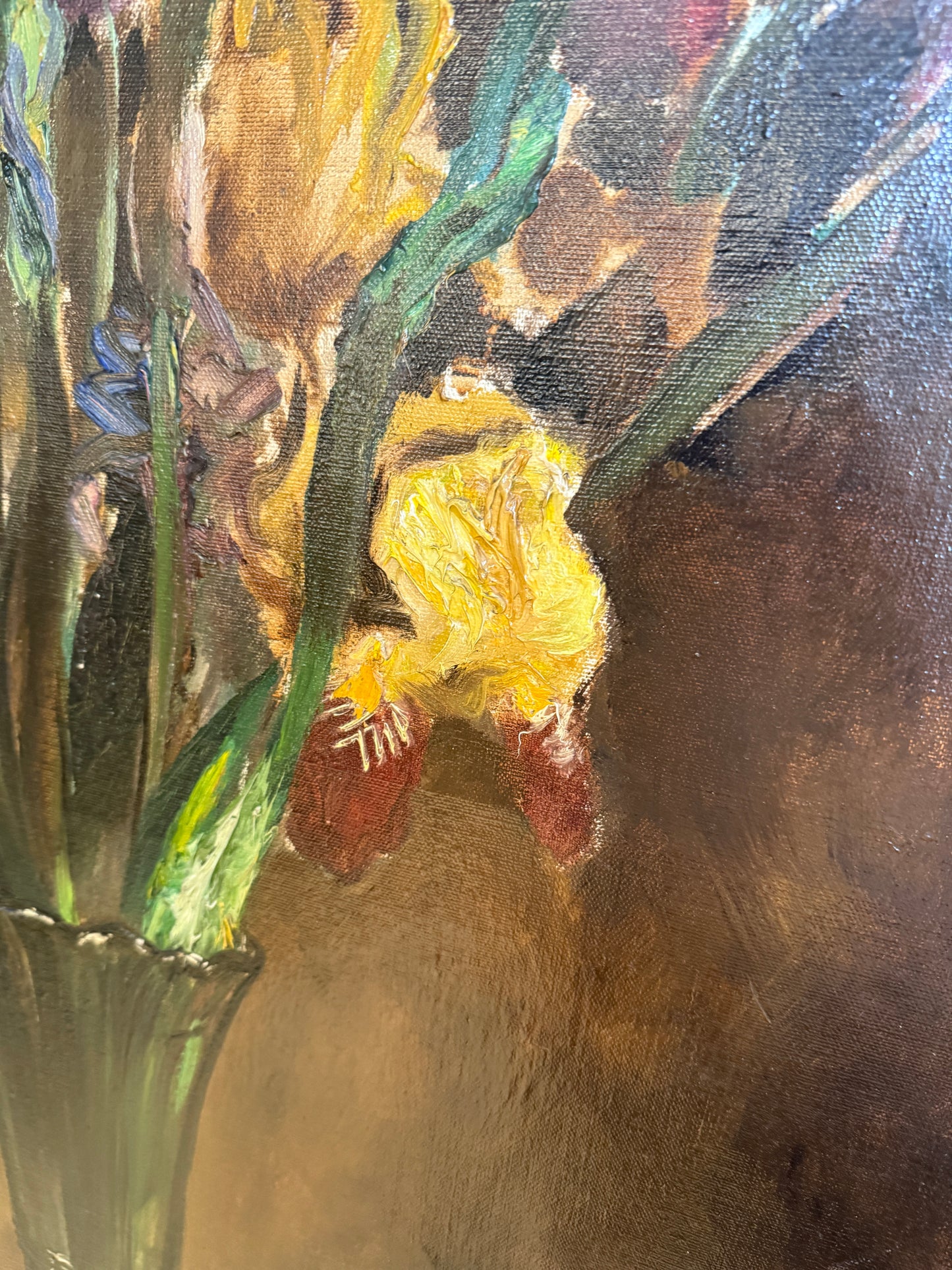 An impressionistic oil painting of yellow irises with green leaves and stems against a dark brown background.