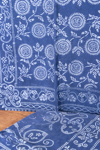 Blue and white patterned fabric, likely cotton bandana or tablecloth, folded to show its detailed floral and paisley block print design.