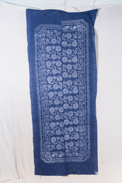 A rectangular indigo blue fabric panel with a white printed floral and geometric border pattern, laid flat on a white fabric background.