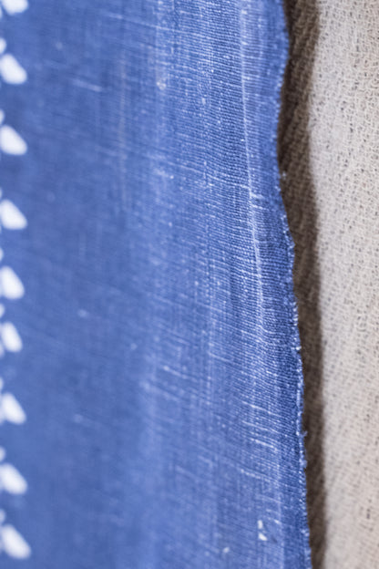 Close-up of a blue woven fabric with white dotted pattern along the edge, next to a beige textured fabric.