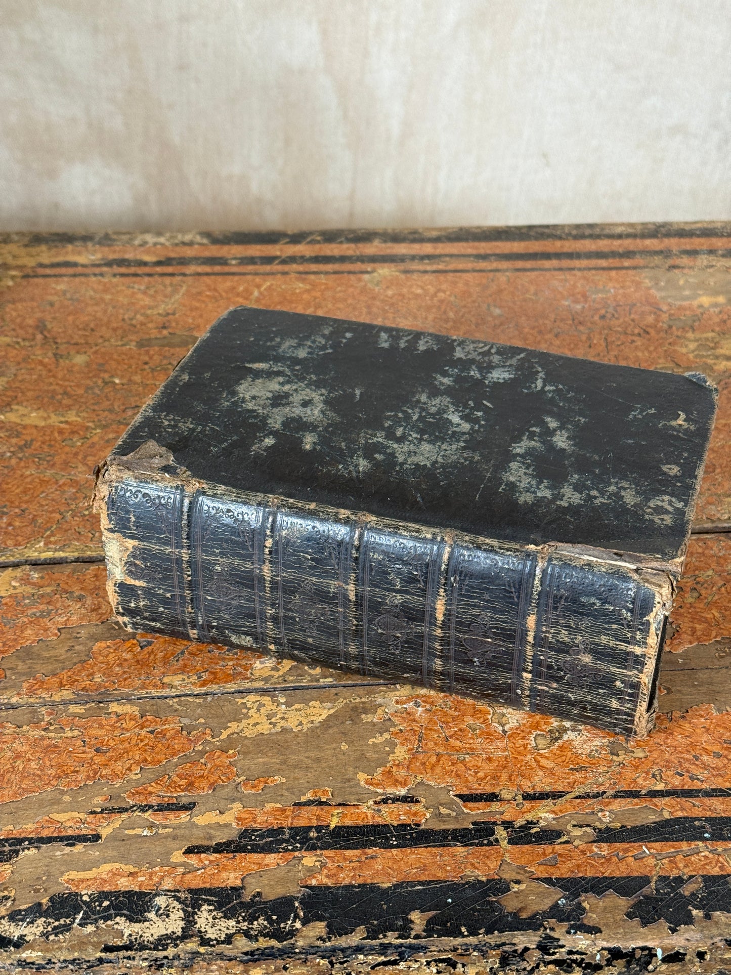 Close-up of an old, worn book with dark leather spine and peeling cover.