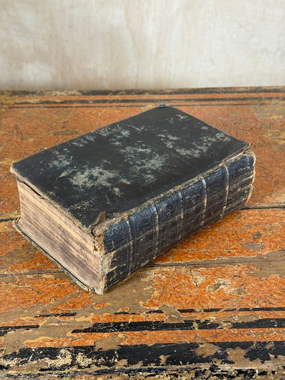 Vintage book with worn leather binding on a textured surface