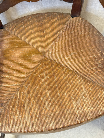 Close-up of a woven seat made of three triangular sections of natural brown rope or straw, attached to a dark wooden frame.