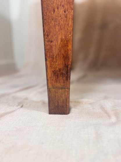 A close-up of a dark brown wooden furniture leg standing vertically on a light beige fabric surface.
