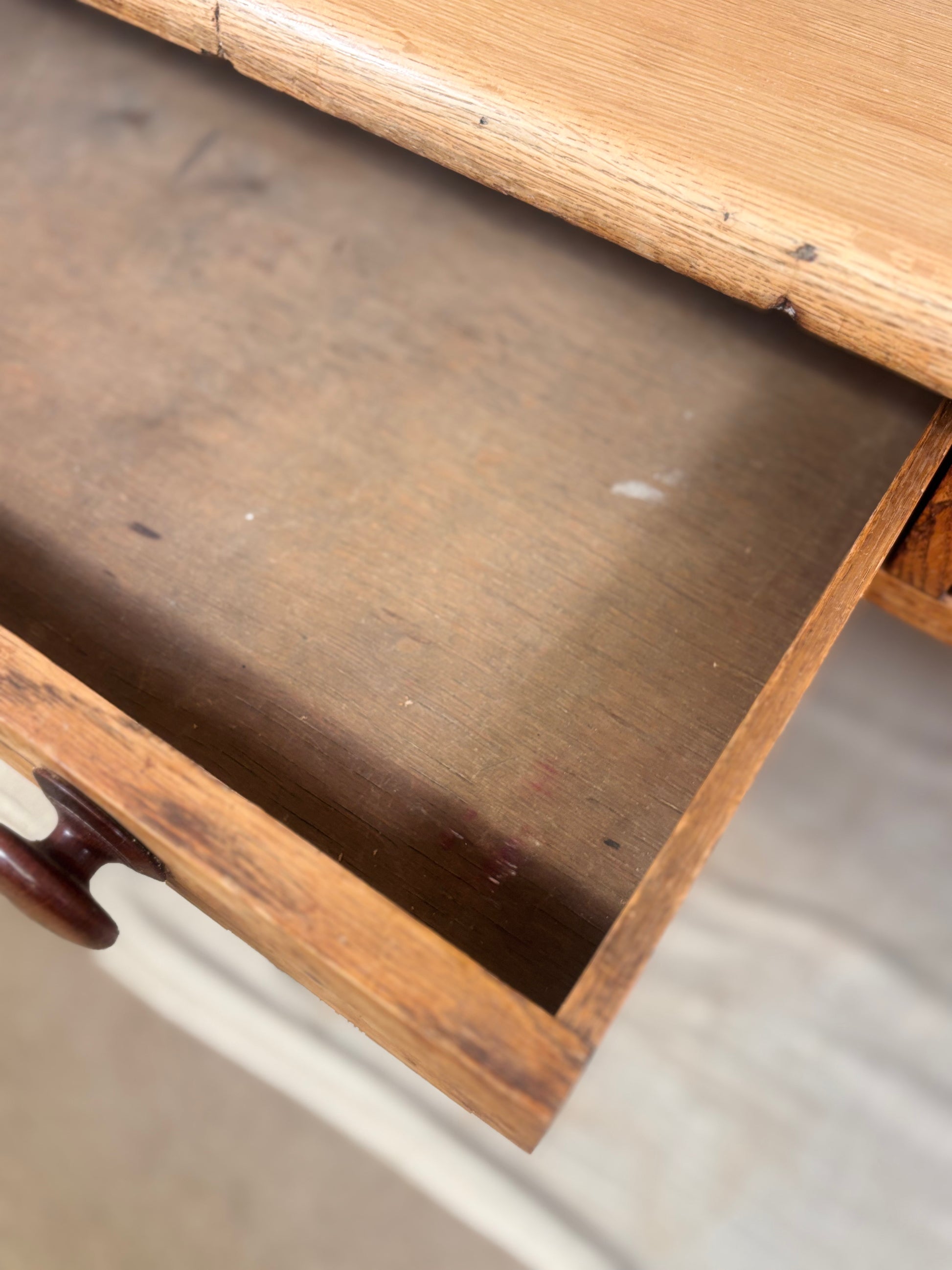 Close-up of an open wooden drawer showing the interior wood grain and a dark brown drawer pull knob.