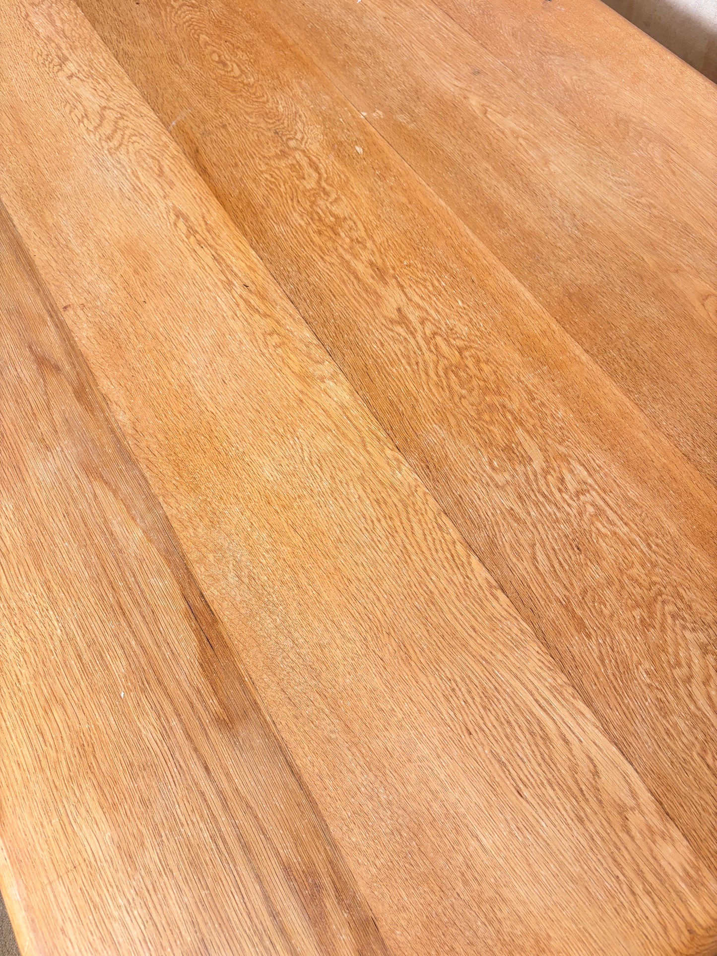 Close-up of a light brown wood surface with visible grain and plank seams.