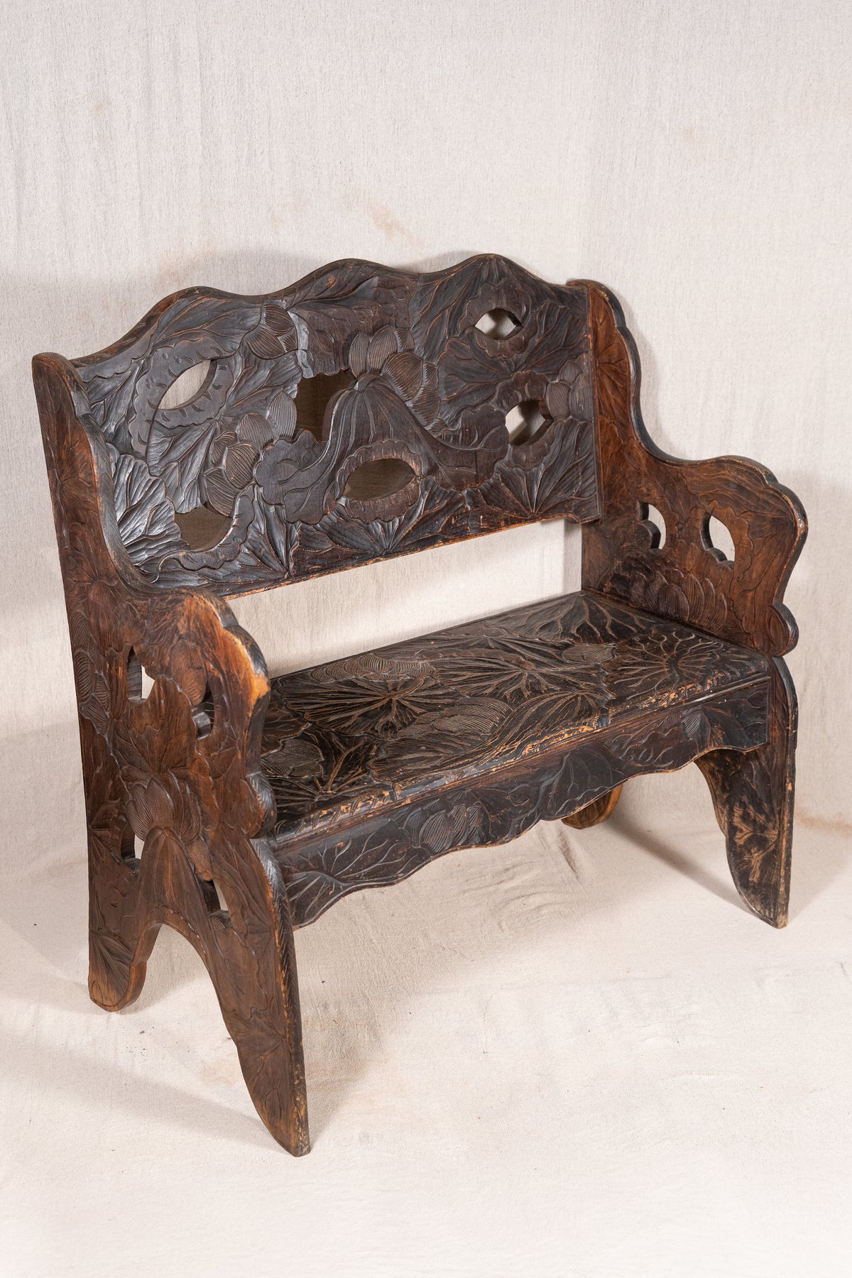 Liberty & Co. Japanese carved hardwood bench, circa 1900–1910, featuring pierced floral panels and intricate decoration from the Arts and Crafts period.