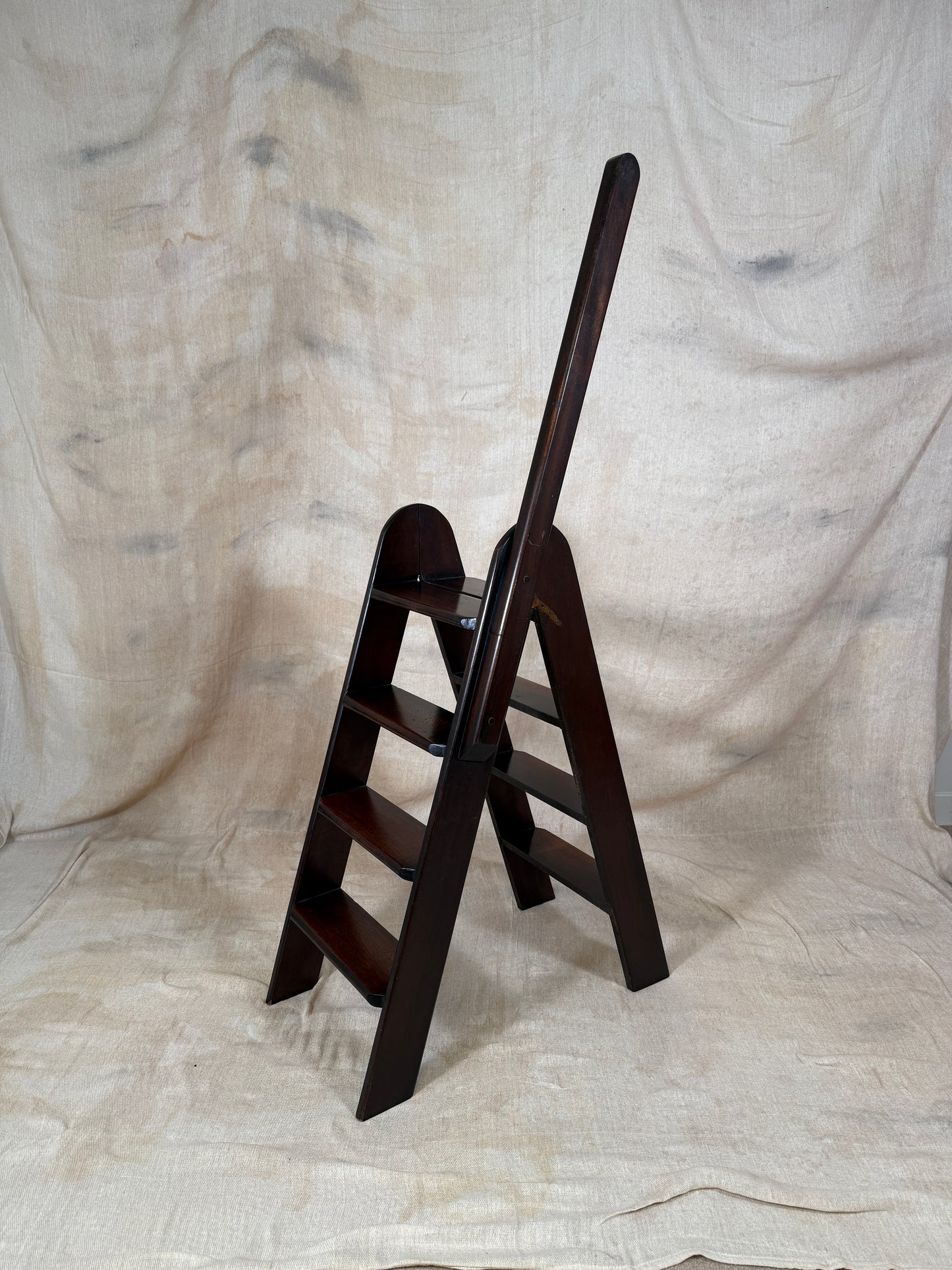 Wooden step ladder on a textured beige fabric background