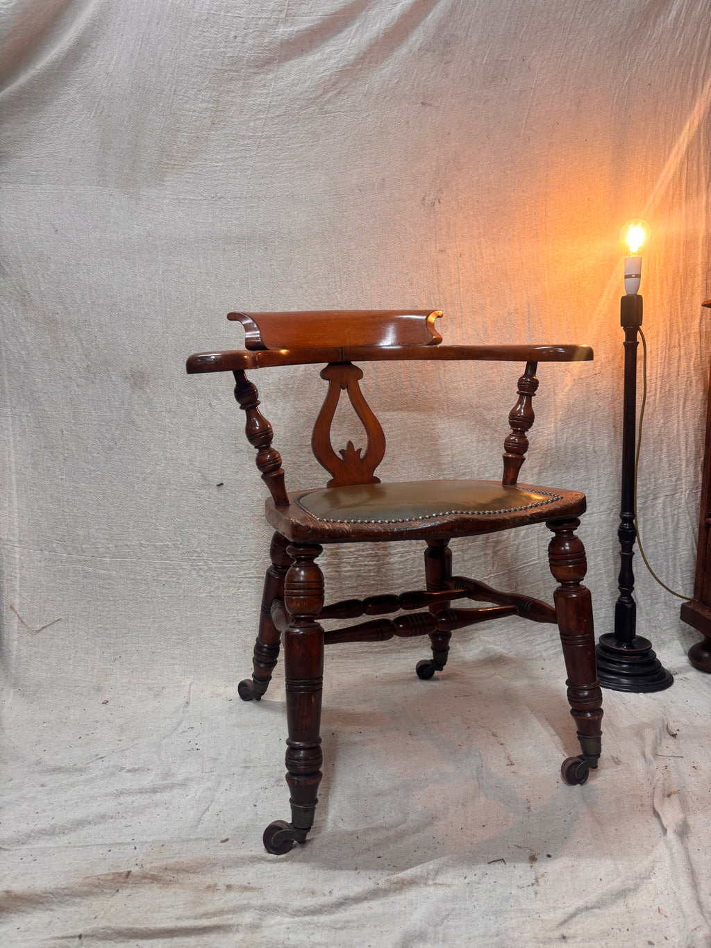 A green leather wooden chair with a lamp against a plain background