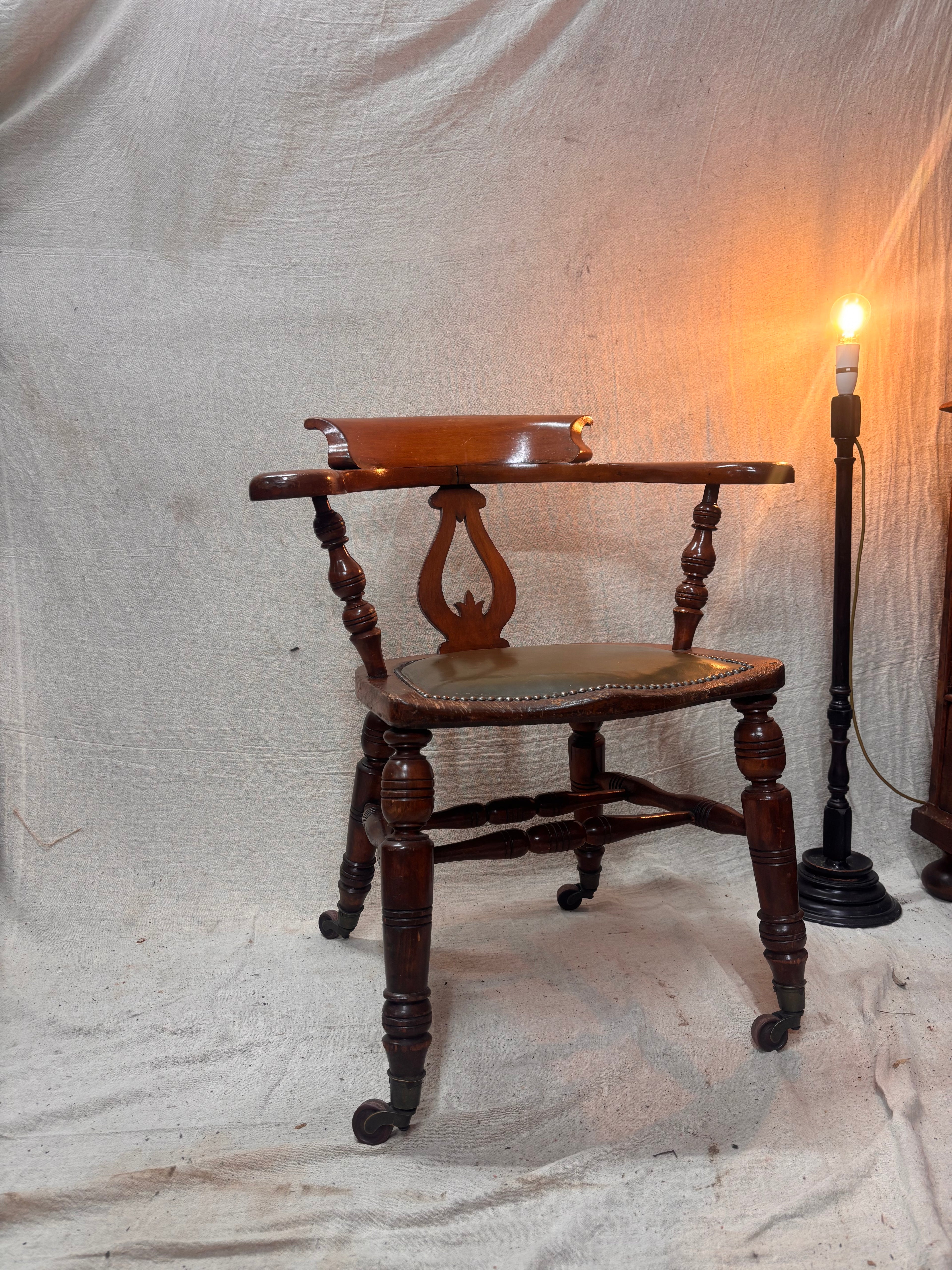A green leather wooden chair with a lamp against a plain background