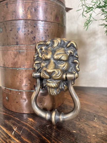 A decorative lion head door knocker in an antique brass finish.