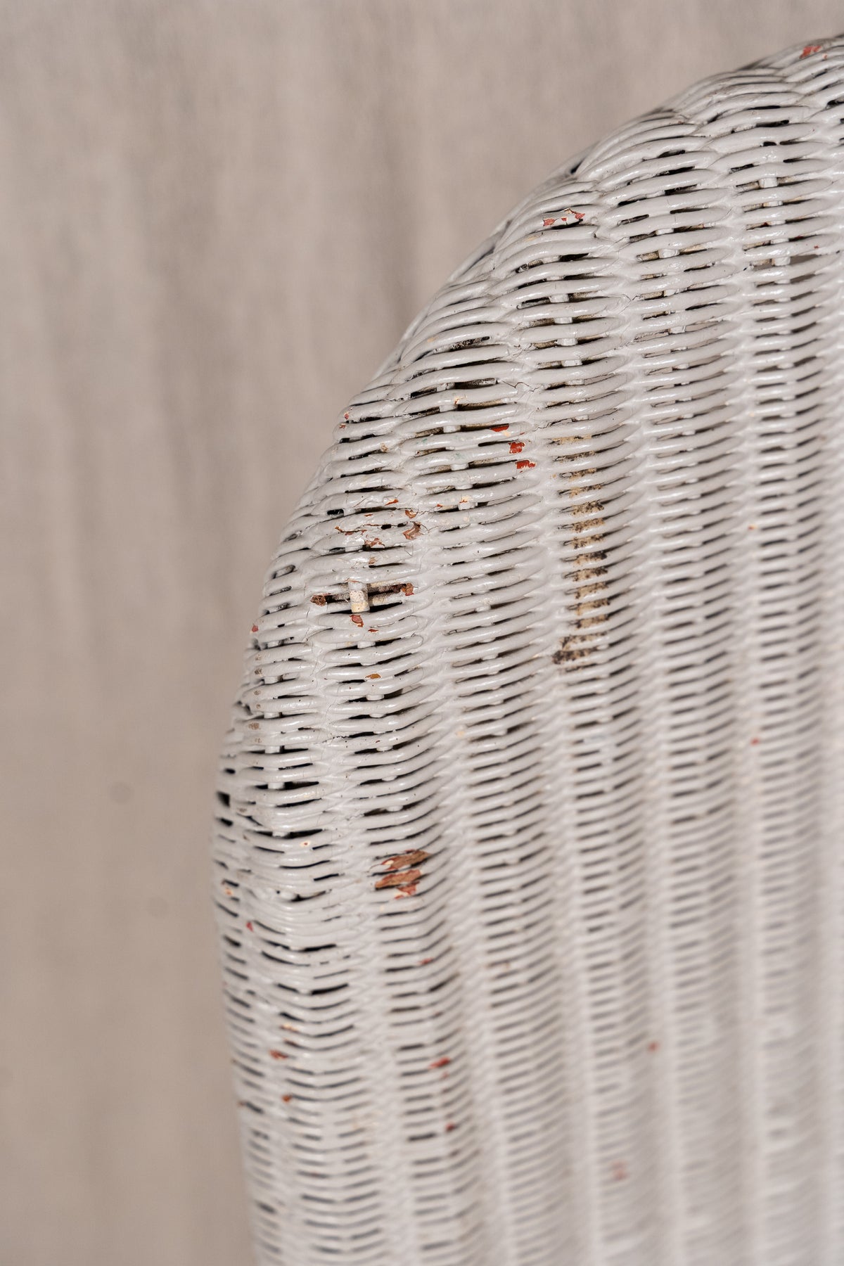 Close-up of a white woven wicker chair back showing the detailed texture of the interlaced slats against a neutral beige background.