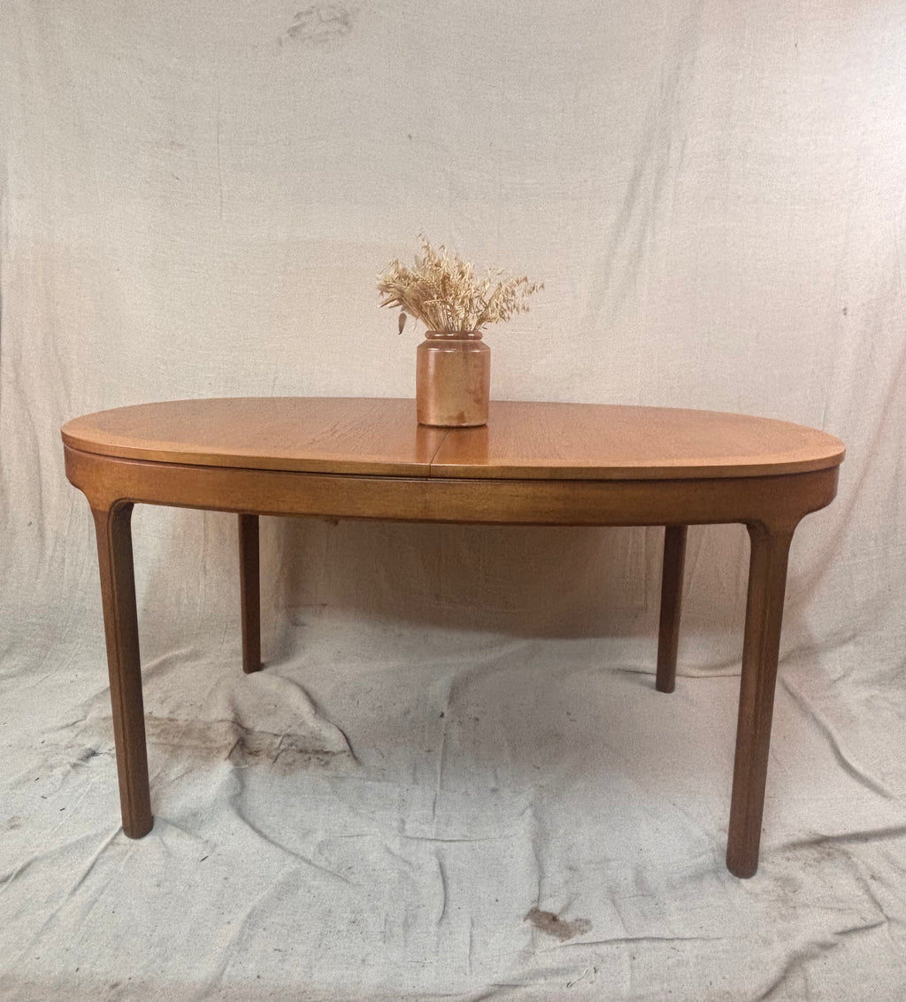 a wooden table with a vase of dried flowers on a cloth background