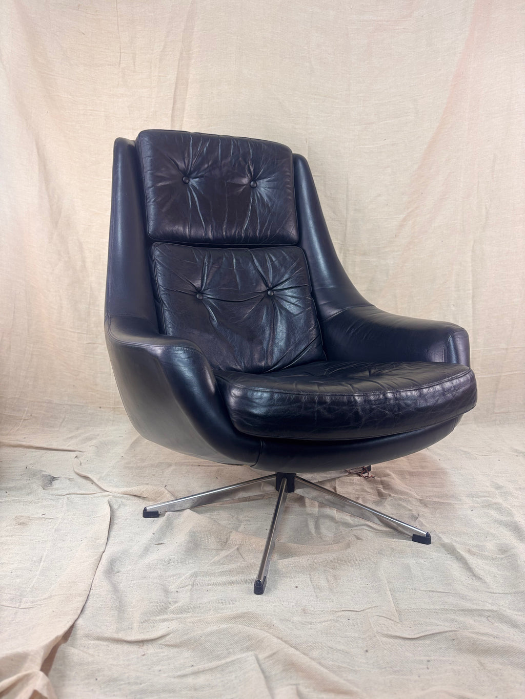 A black leather swivel chair on a cream cloth background 
