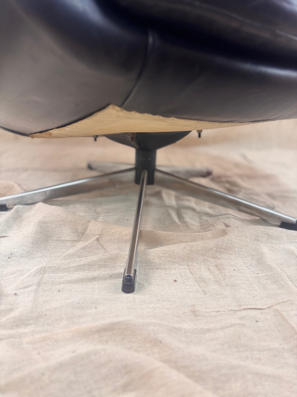 Close-up of a black swivel chair on a plain floor.