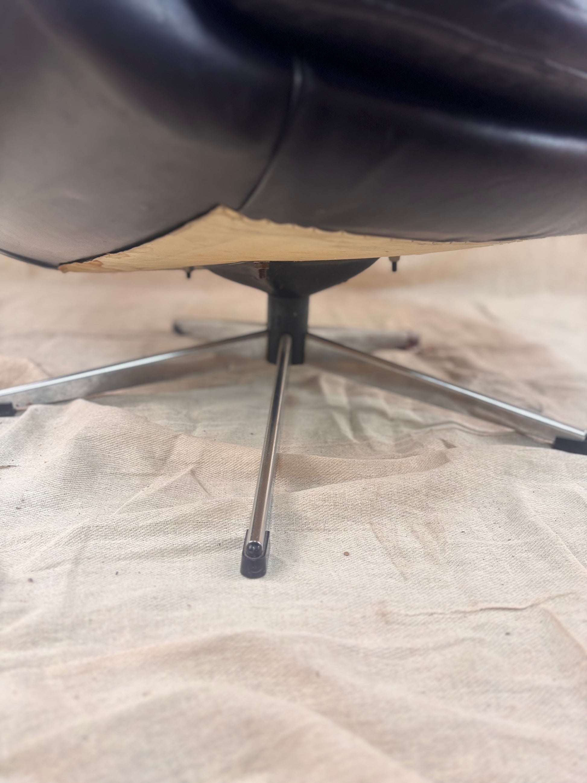 Close-up of a black swivel chair on a plain floor.
