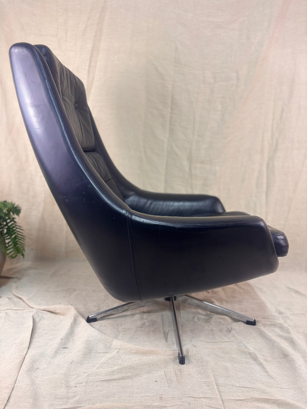 Black leather chair with chrome base on a beige fabric background