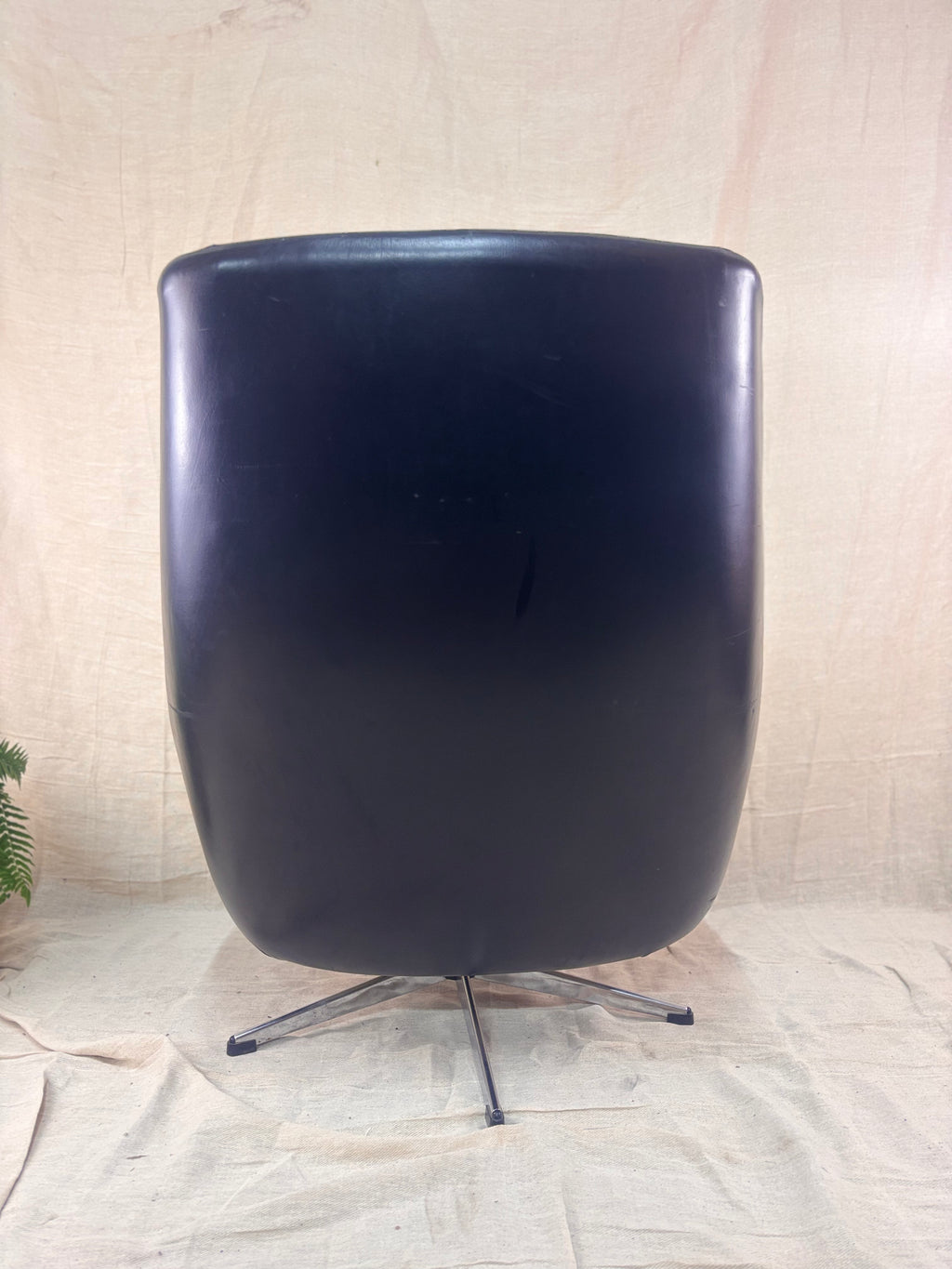 Black chair with a metallic base on a textured beige background