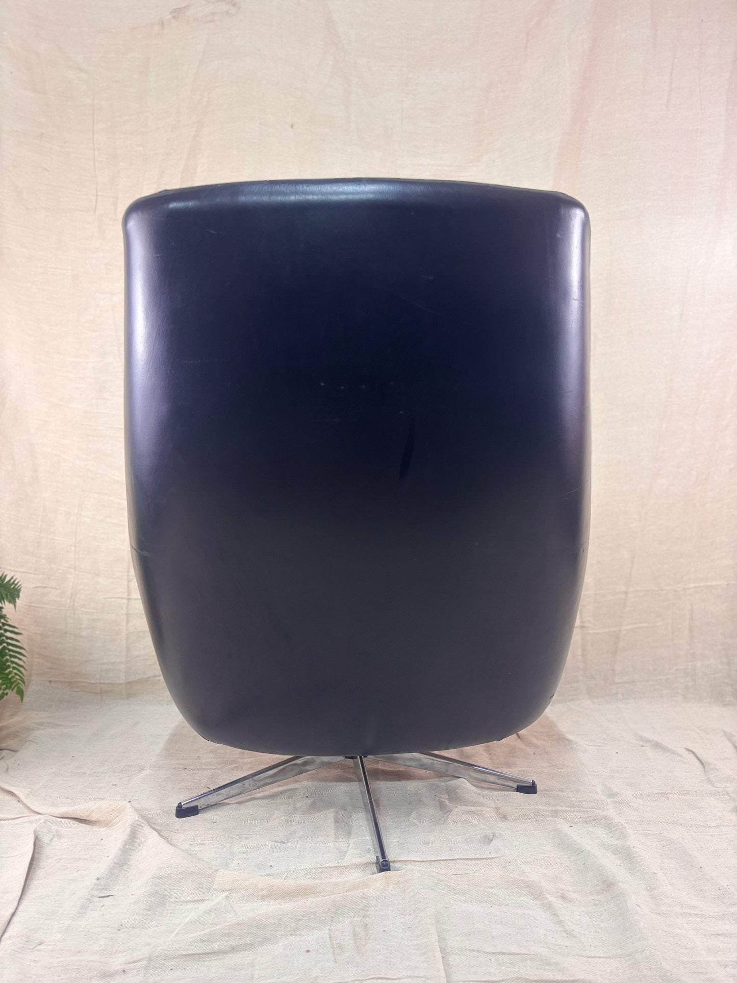 Black chair with a metallic base on a textured beige background