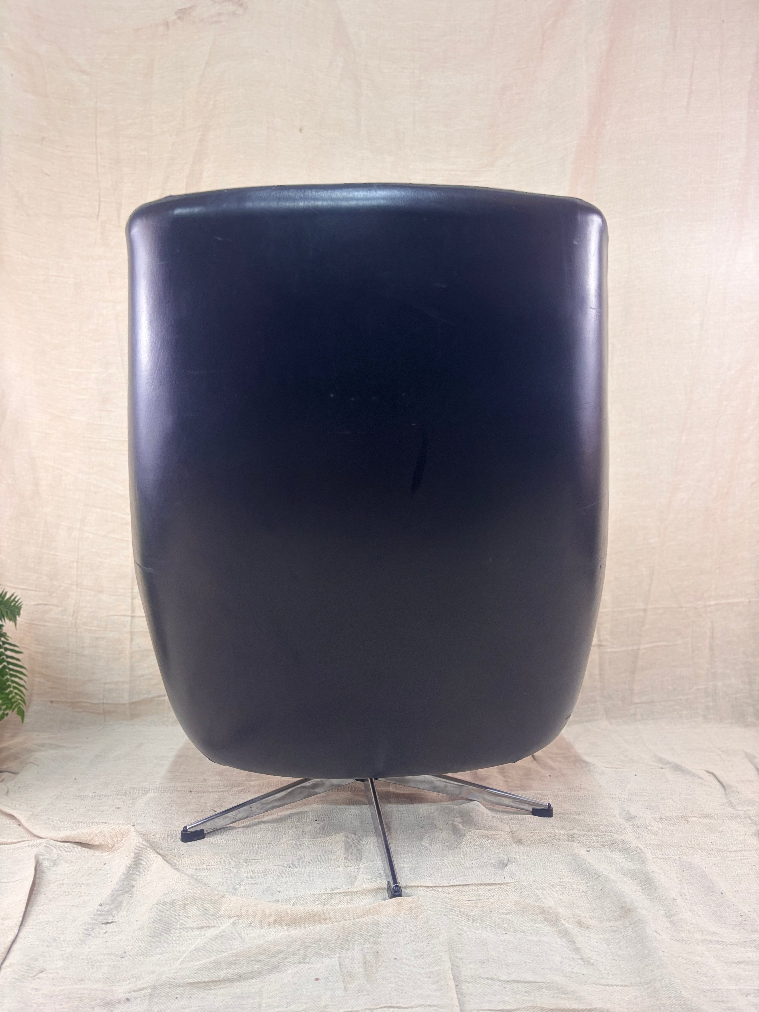 Black chair with a metallic base on a textured beige background