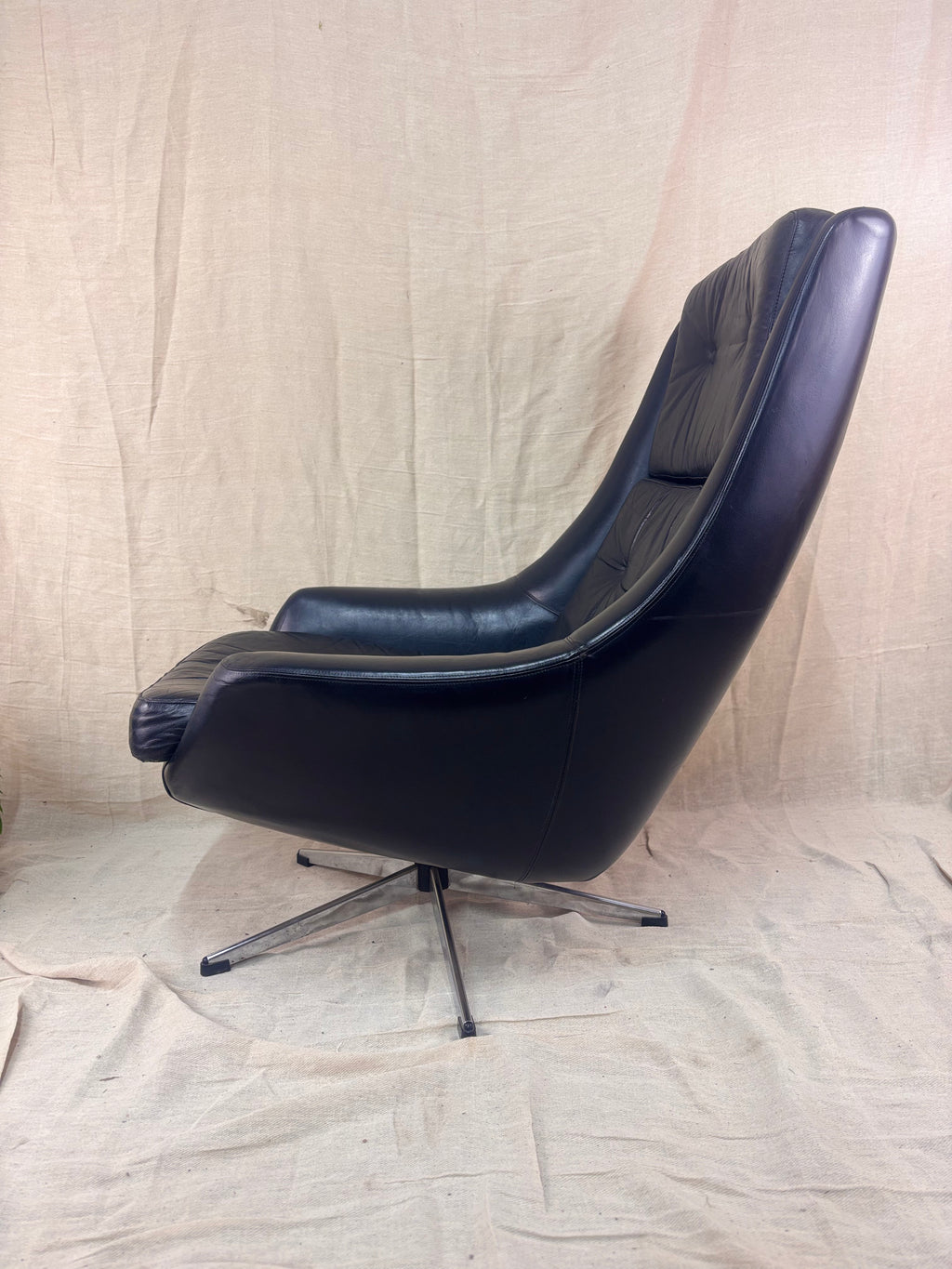 Black leather swivel chair on a beige fabric background