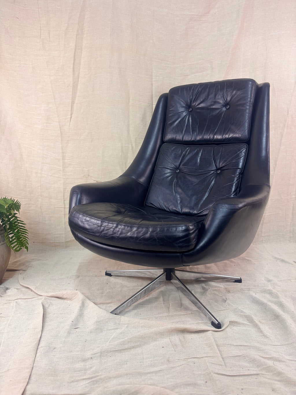 Black leather swivel chair on a beige fabric background