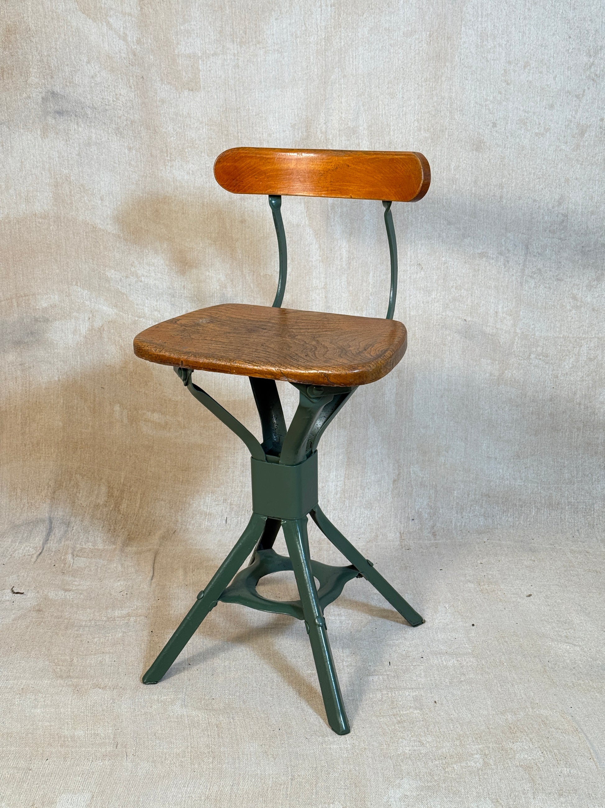 Vintage industrial machinist chair with green steel frame, wooden seat. 